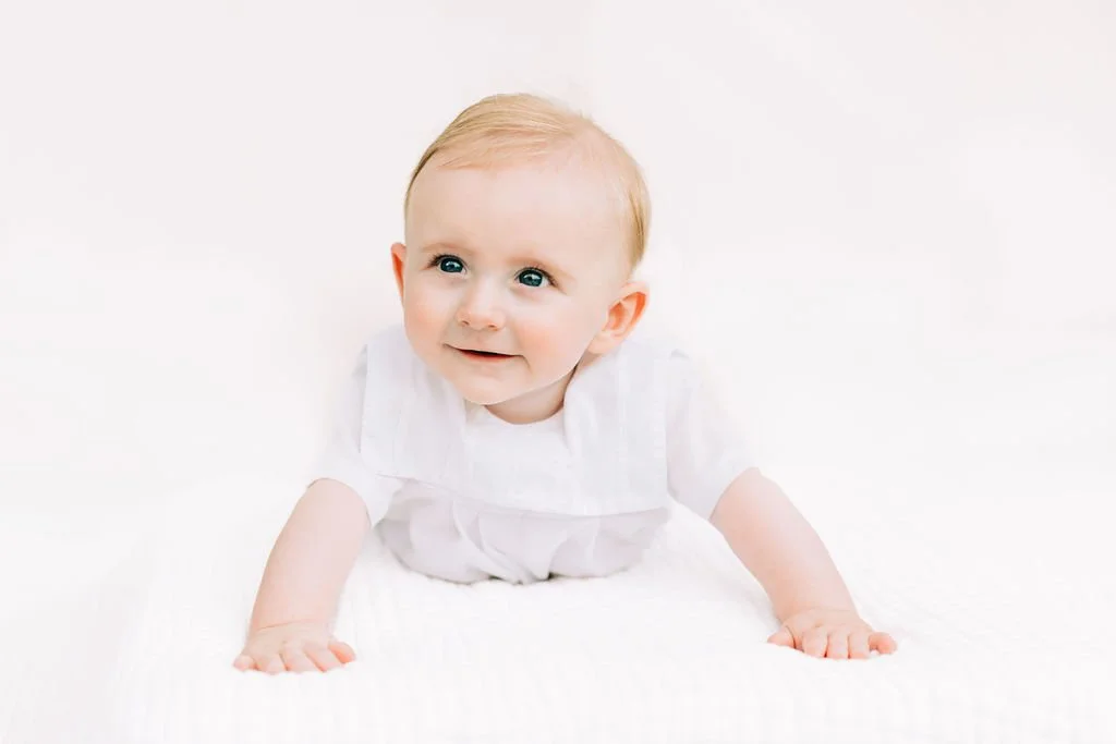 6 month baby boy smiling during milestone session in Baton Rouge with white backdrop