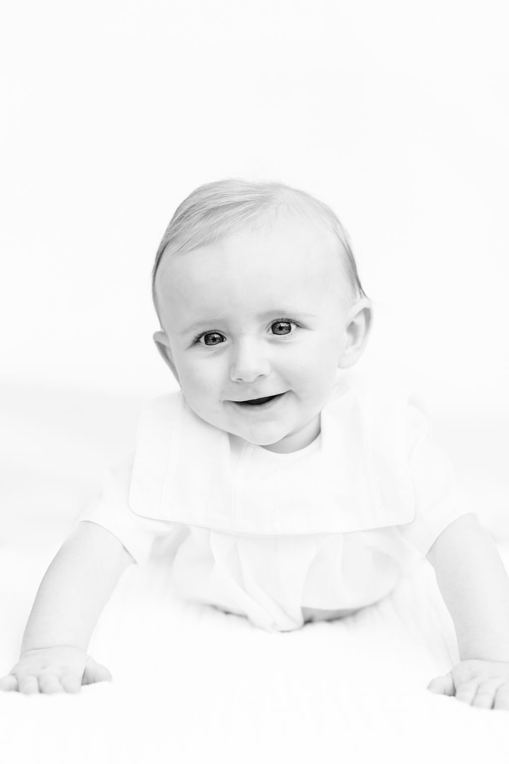 black and white baby sitting and smiling during 6 month photo session Baton Rouge