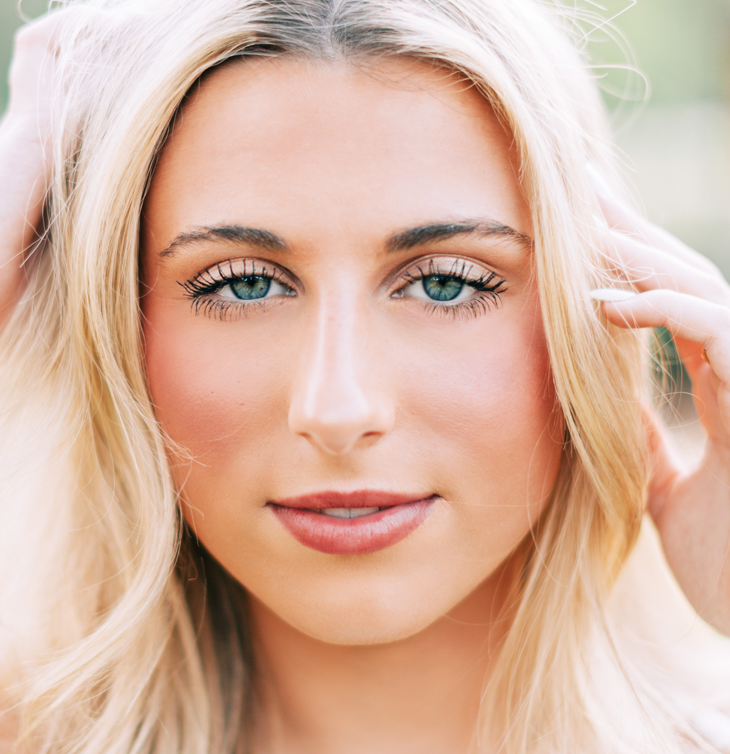 high school senior girl smiling softly in a floral outdoor setting during a baton rouge senior portrait session