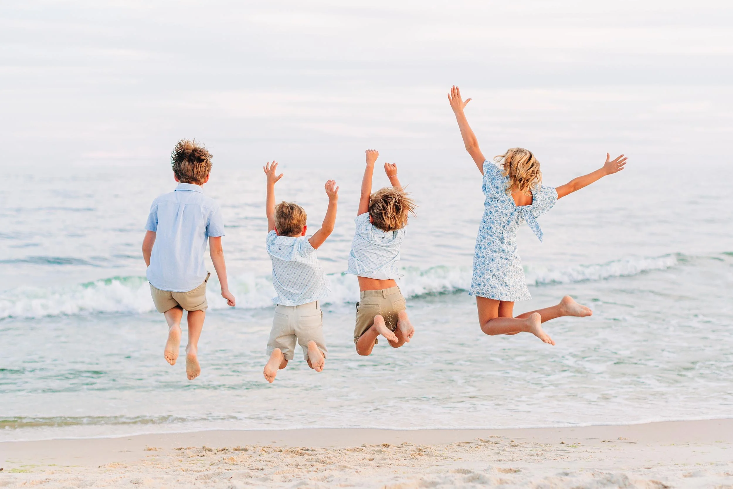 Children jumping and playing in the ocean waves at the beach.