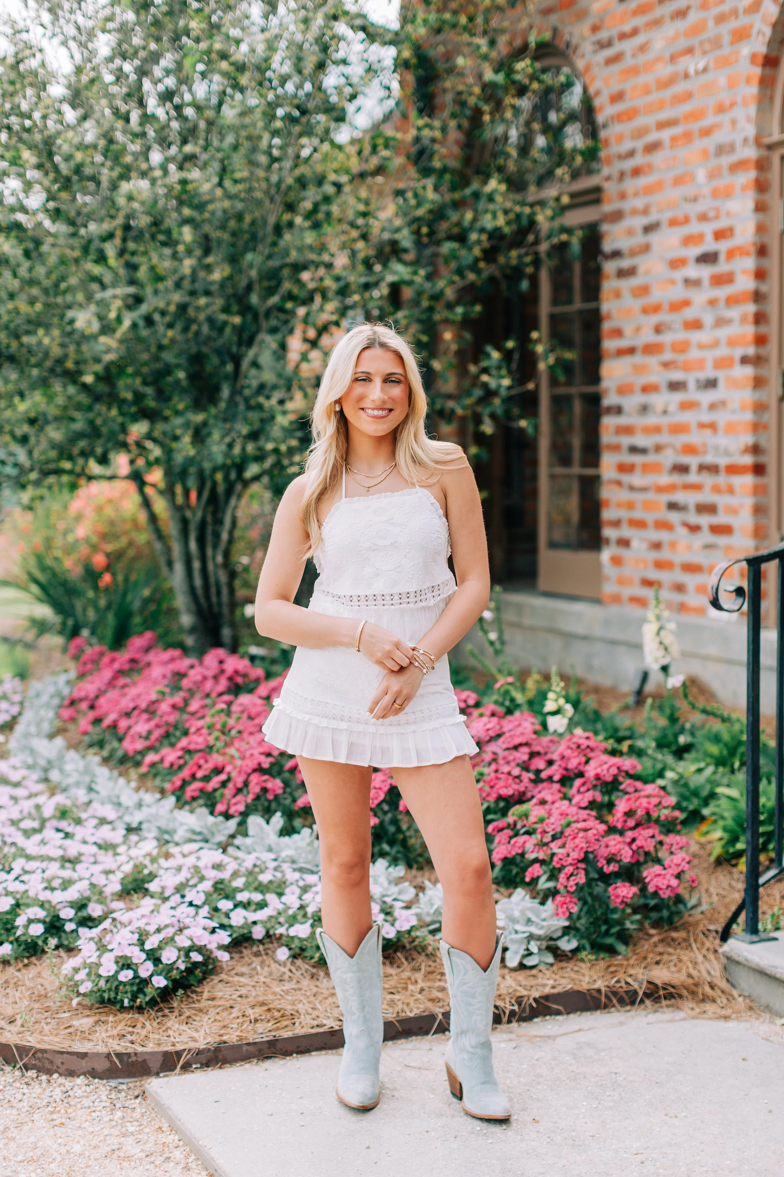 baton rouge senior portraits at burden gardens, blond haired girl standing in front of red brick building in white top and skirt
