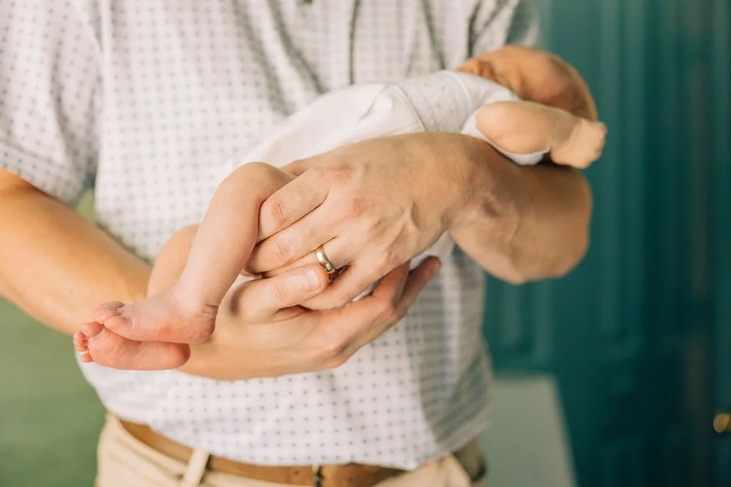 A person in a hospital gown holding a small puppy.