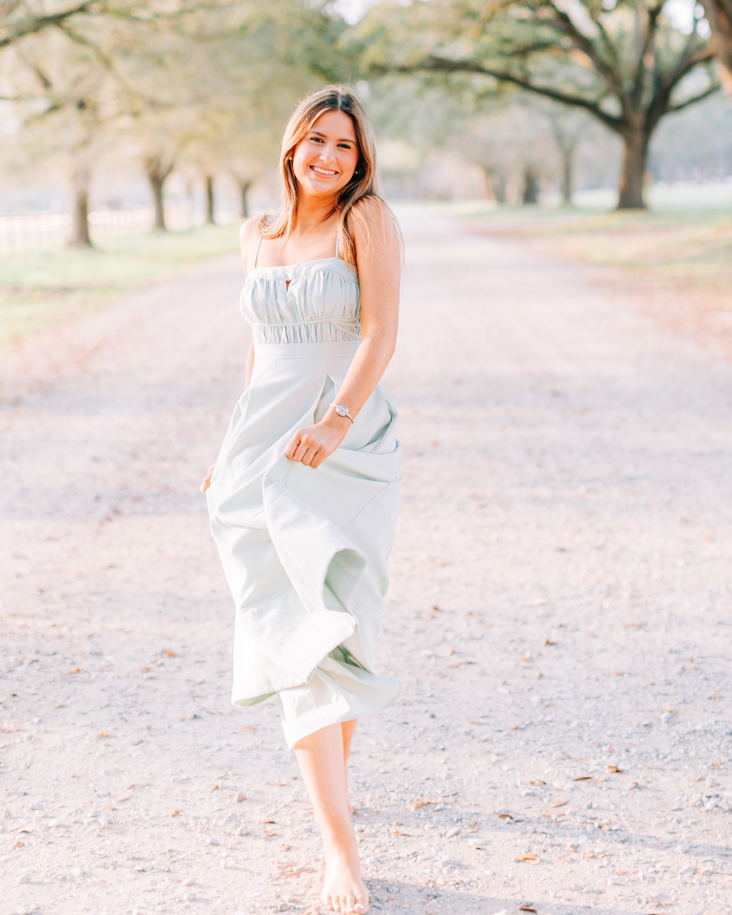 High school senior walking down gravel road in flowy dress during Baton Rouge session