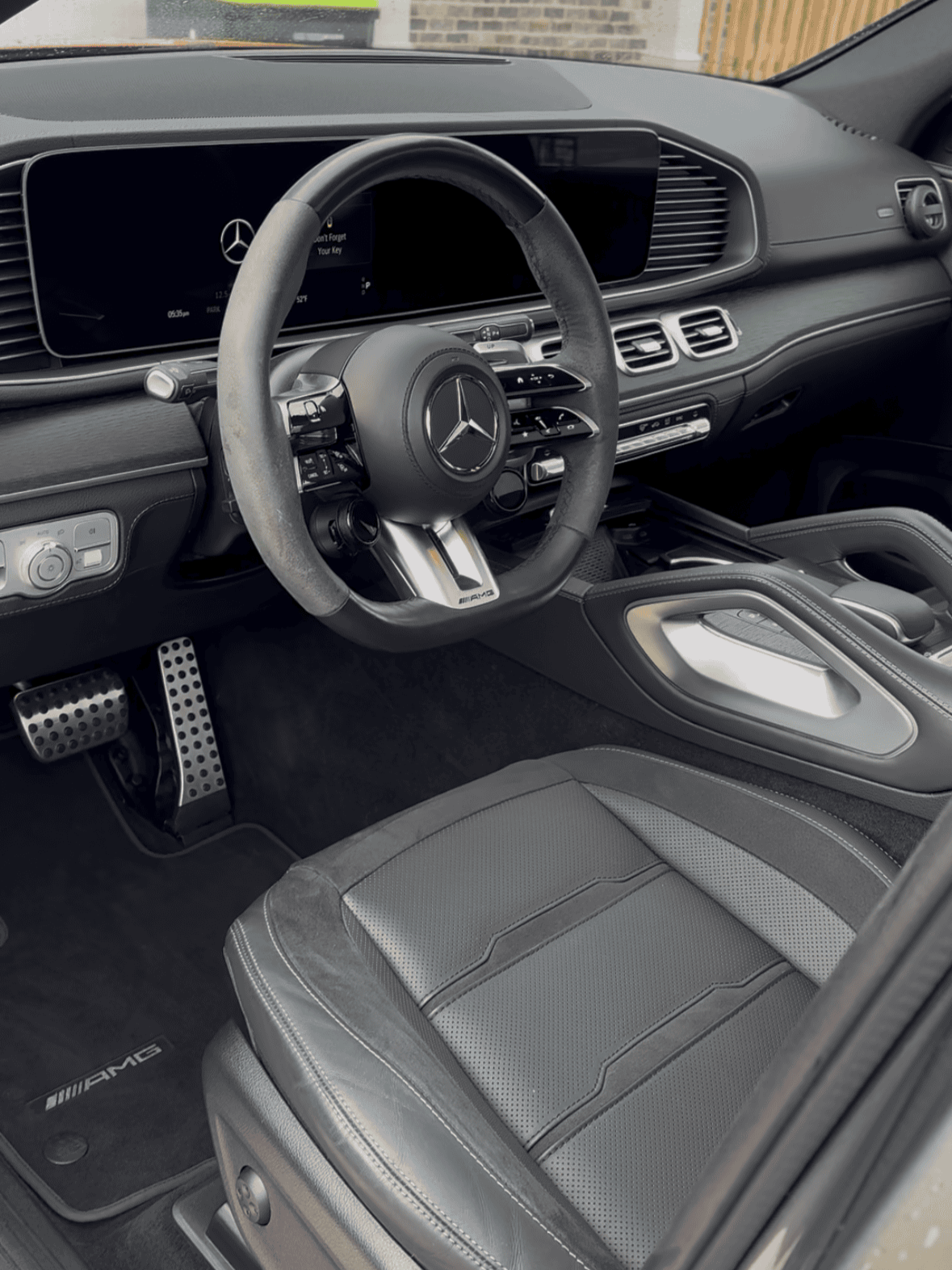 The interior of a Lexus car, featuring a wooden steering wheel, black dashboard with wood accents, and a center console with an array of controls and a gear shift.
