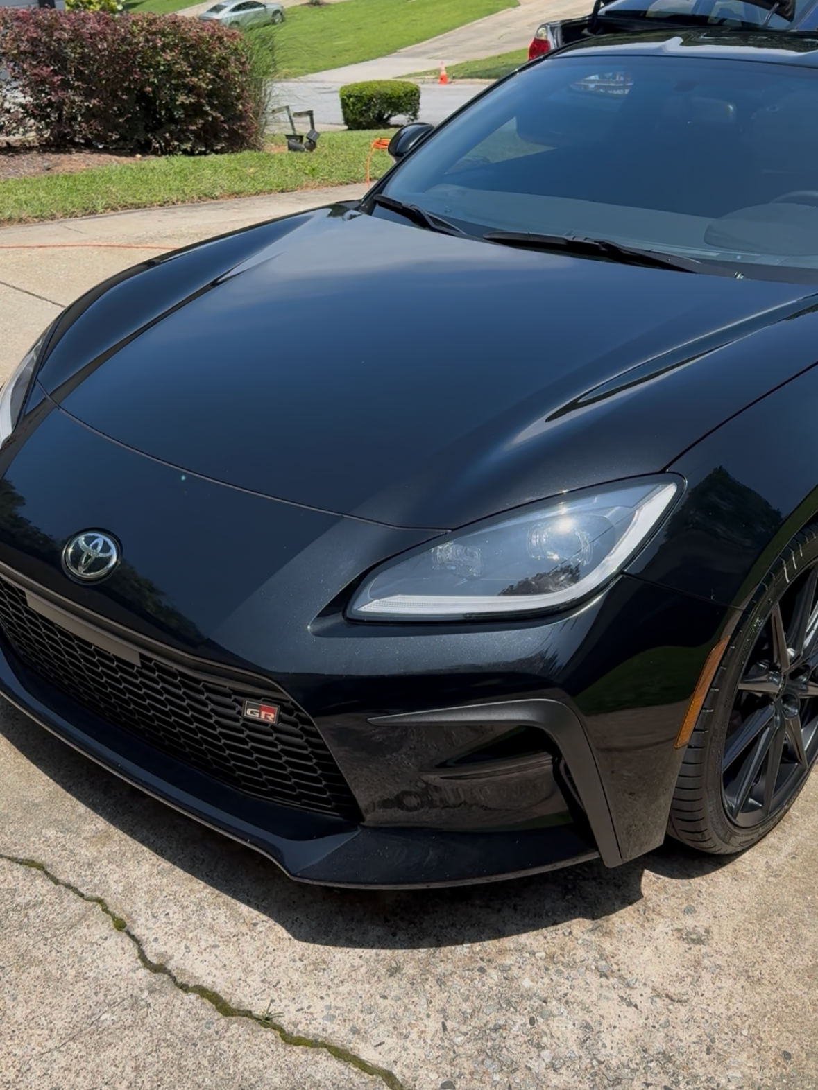 Black Toyota sports car parked on a concrete driveway.