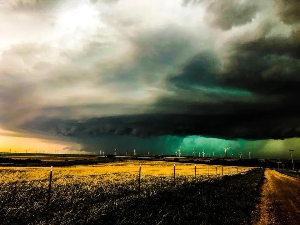 Stormy sky over a field with wind turbines and a dirt road