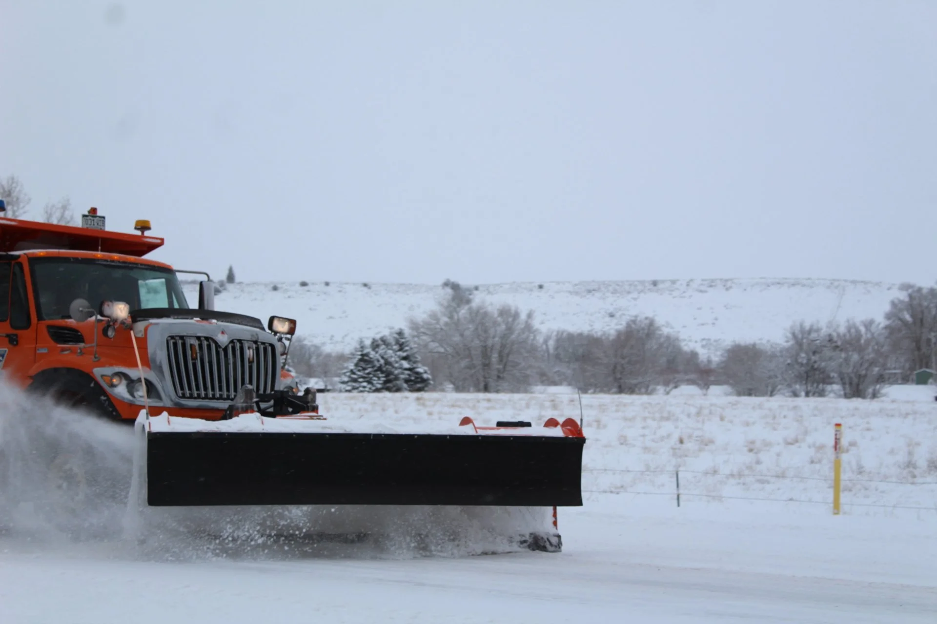 Snowplow clearing snow on a road in a snowy landscape