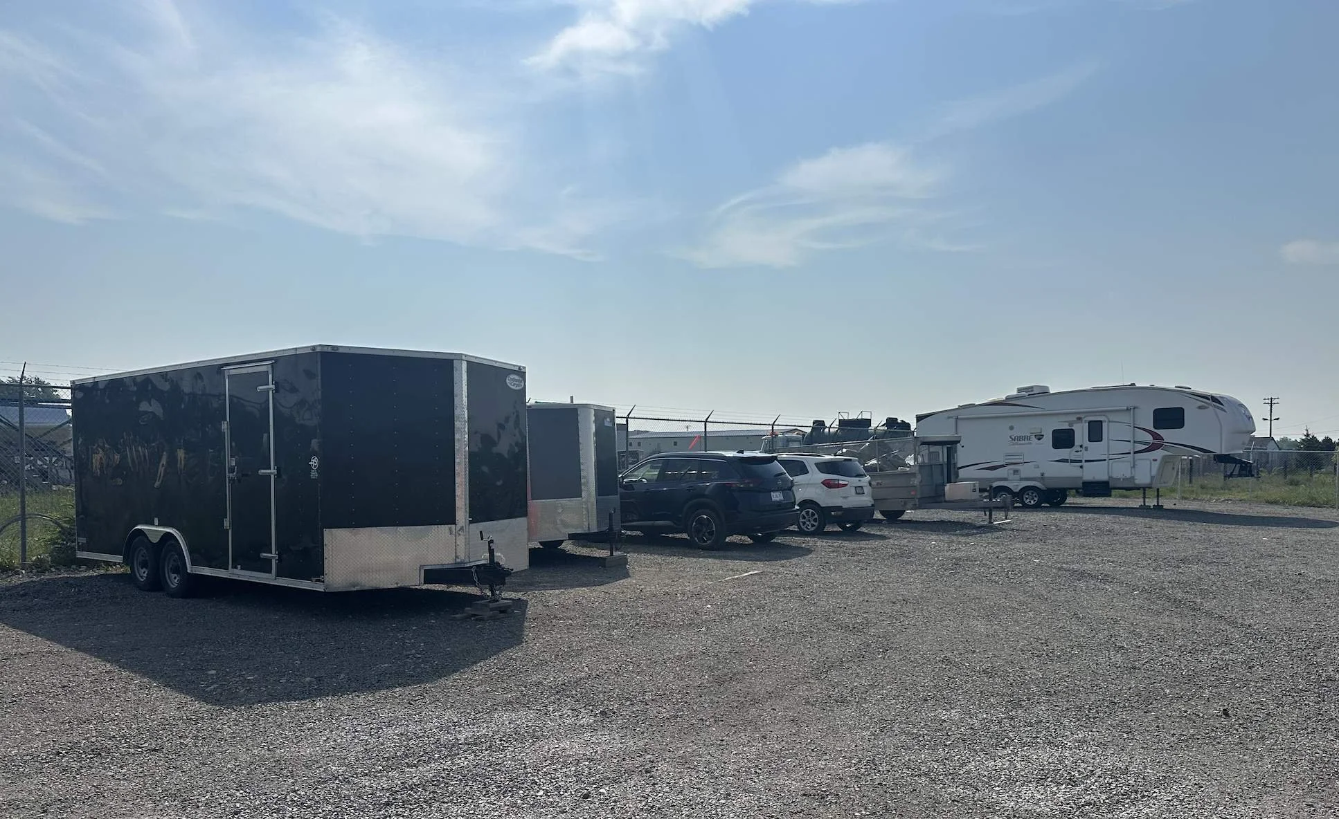 Enclosed trailer and RVs parked in CoastGuard's gravel outdoor parking lot