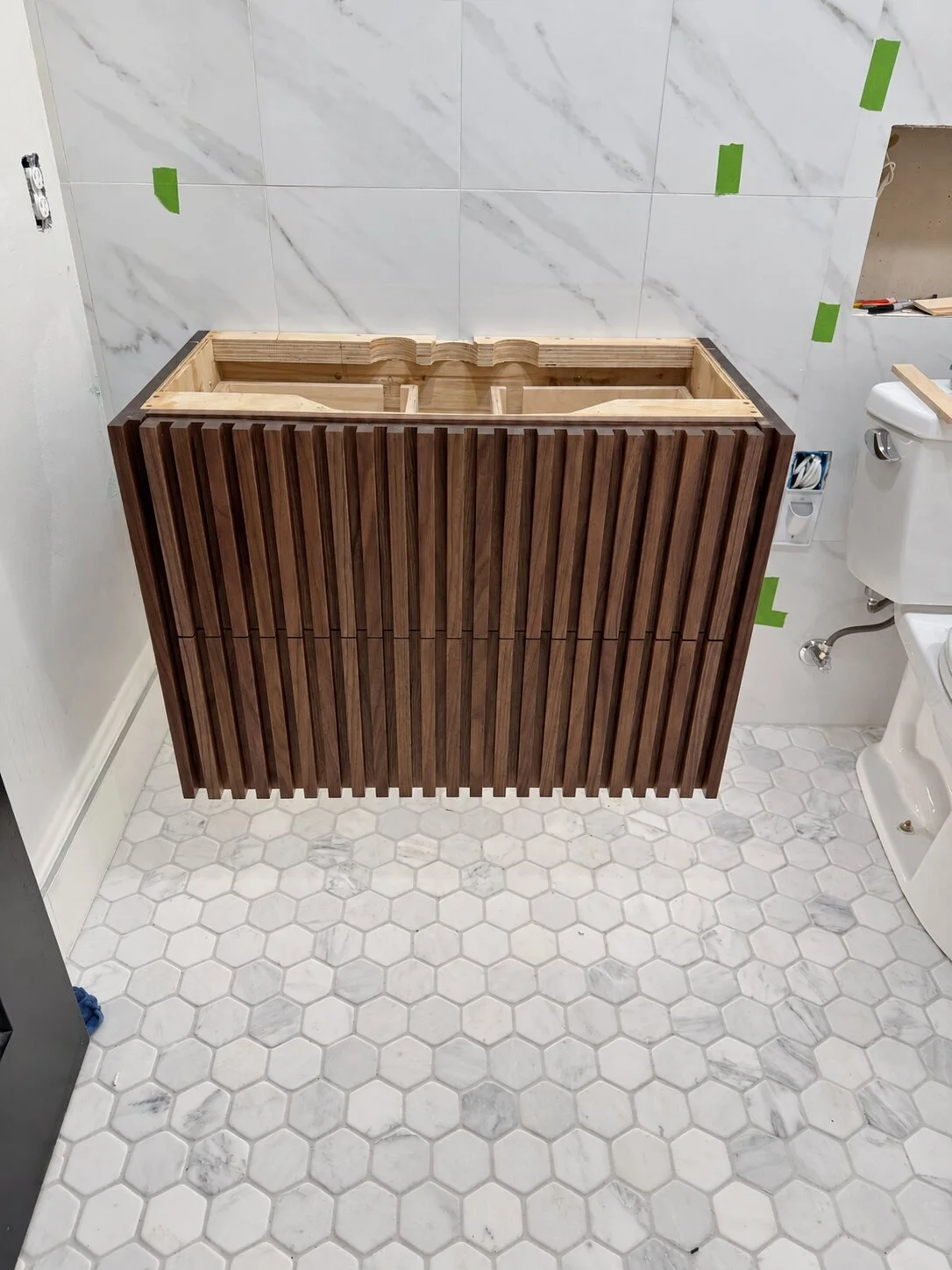 Solid walnut floating vanity with sculpted drawer fronts and concealed hardware without quartz counter top.