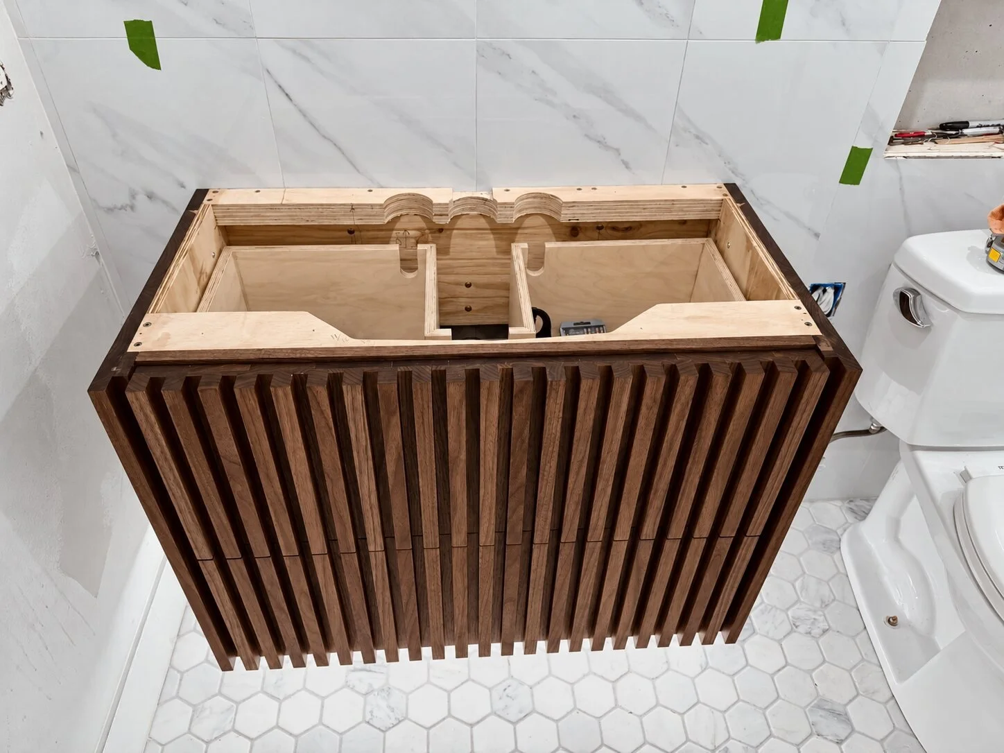 Solid walnut floating vanity with sculpted drawer fronts and concealed hardware without quartz counter top.
