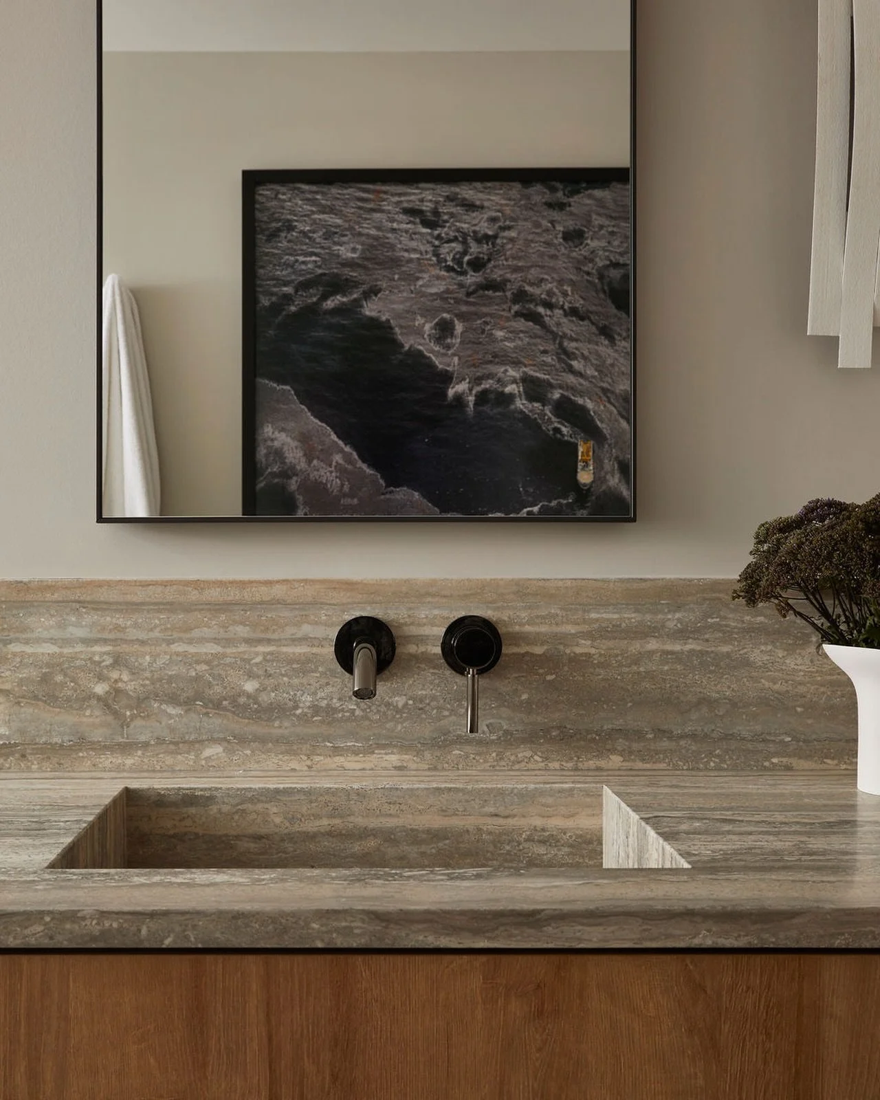 This fully integrated stone sink quietly steals the show in the primary bathroom.

The real magic, though, is in the details. Positioning this Burtynsky behind the vanity allows it to be experienced twice &ndash; reflected in the mirror and visible f