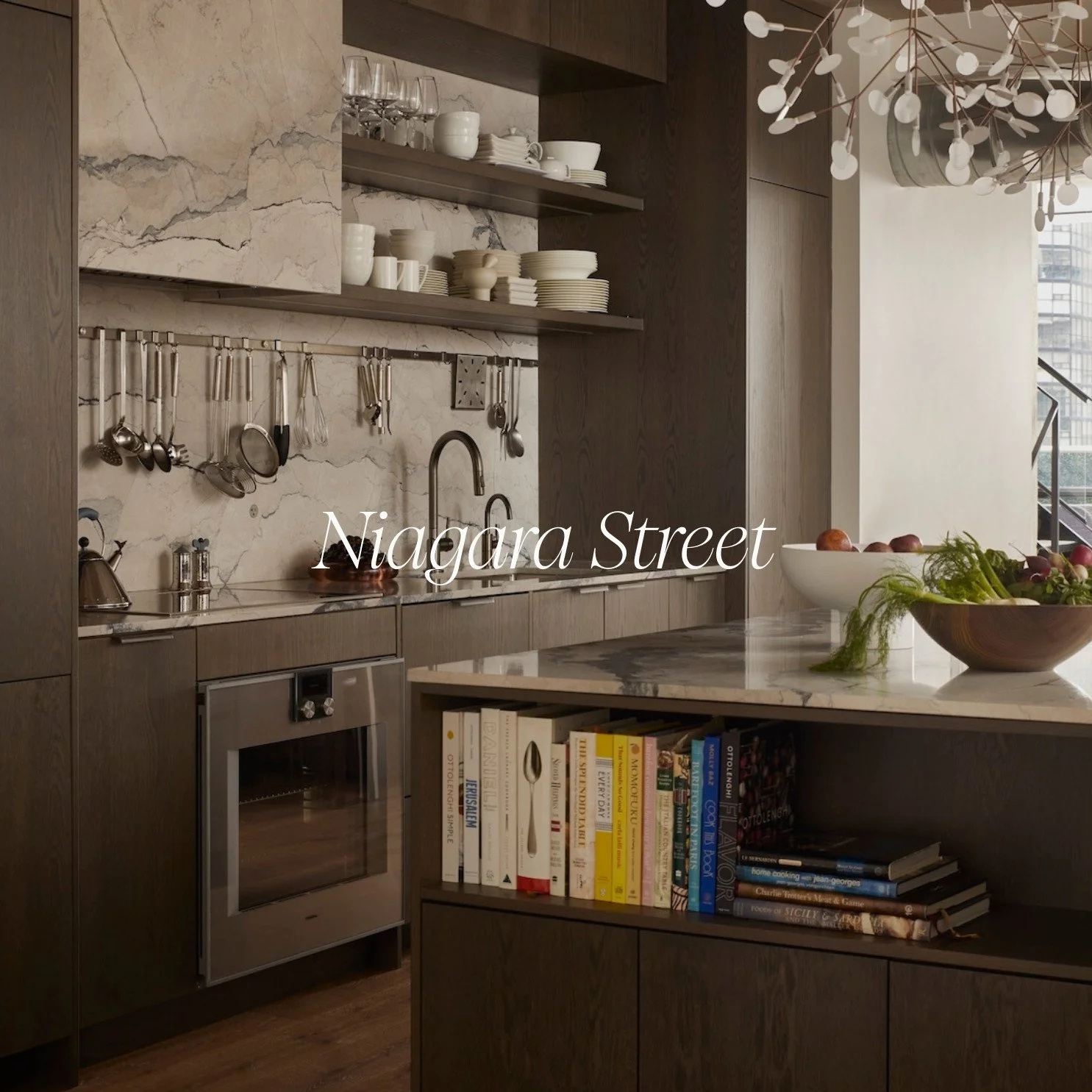 Custom modern kitchen designed by Megan Crosbie Design featuring warm wood cabinetry, open shelving, natural stone backsplash and countertops, integrated appliances, and a functional kitchen island in a Niagara Street condo in Toronto.