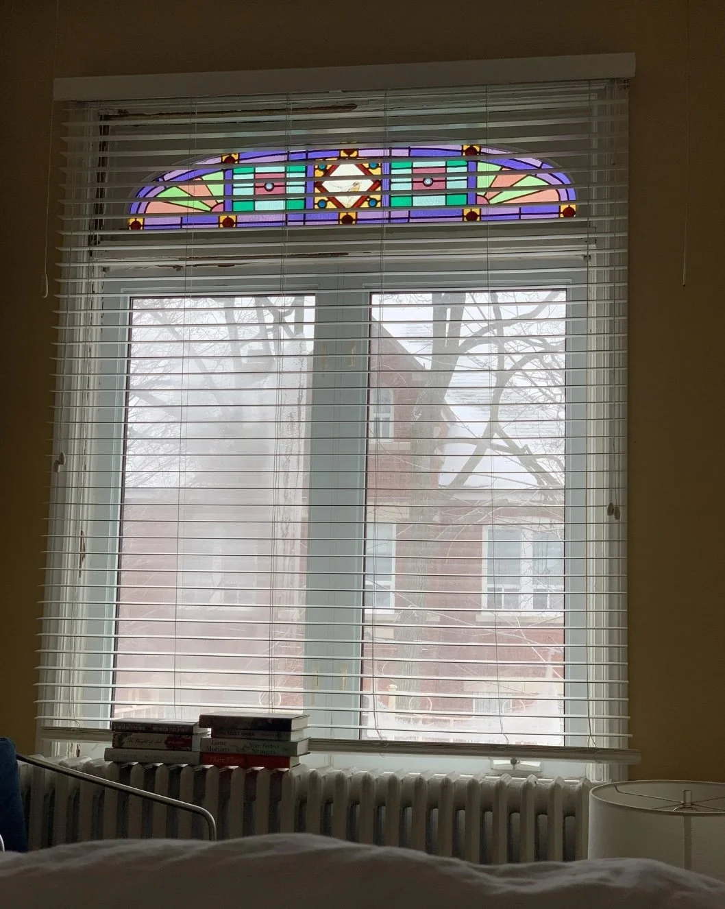 Original stained glass window and radiator in primary bedroom before renovation, Grace Street Victorian home Toronto