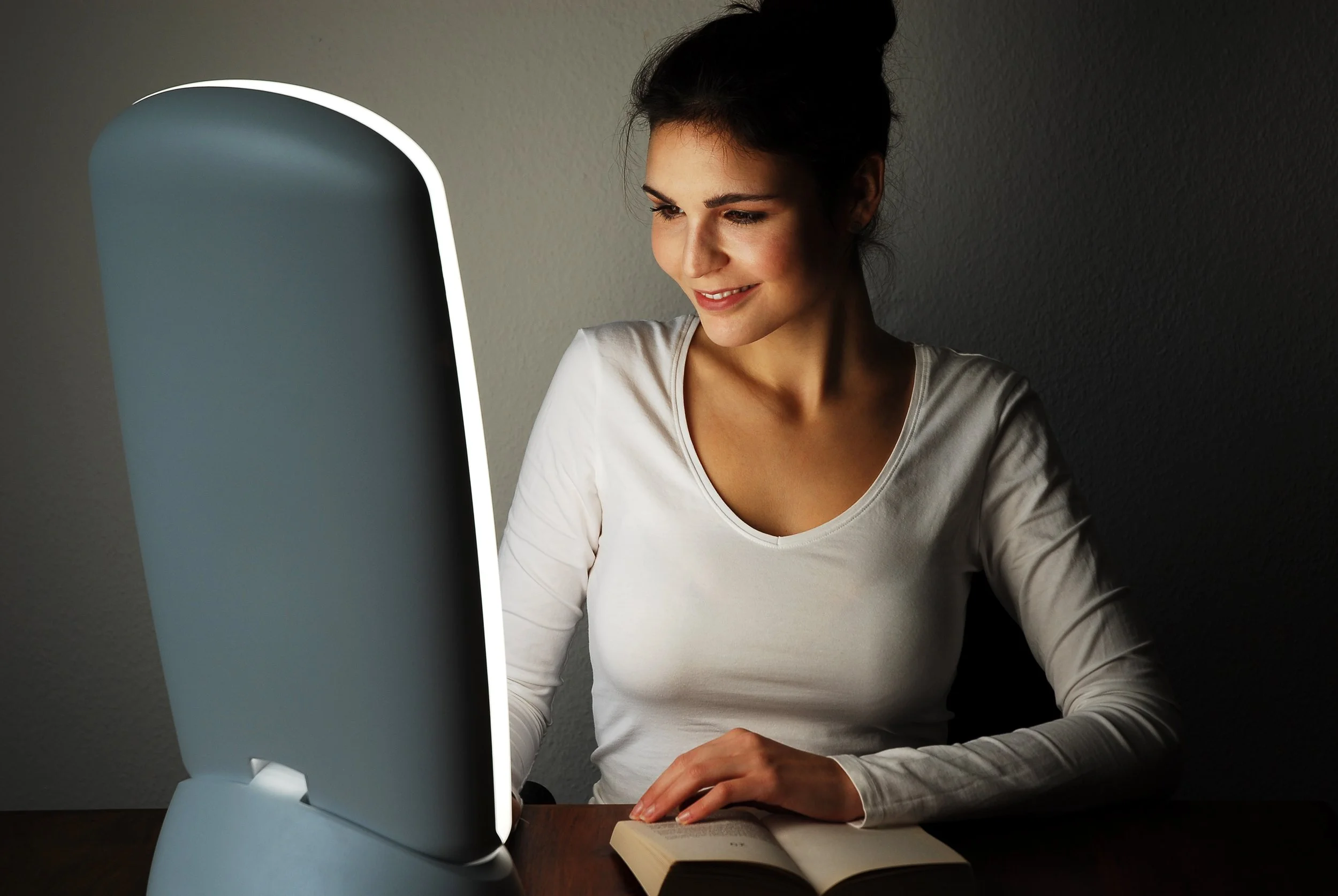 Woman using a bright light therapy lamp for seasonal affective disorder.