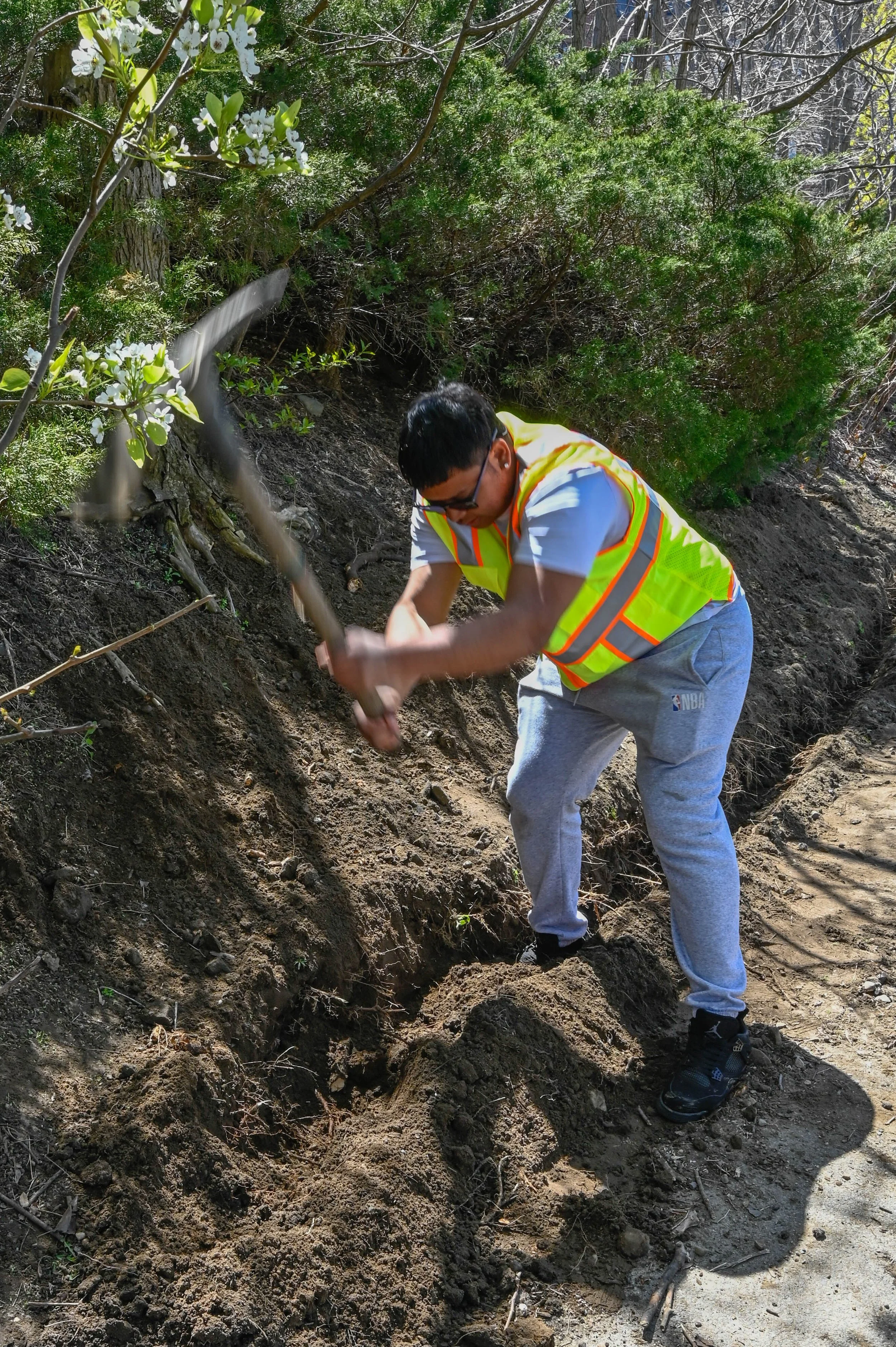 East Boston, MA: April 22, 2024 - Yared, another Climate Corps fellow, works to dig a trough on the side of the path. The team will use this trough to install a silt fence to keep cascading soil at bay.