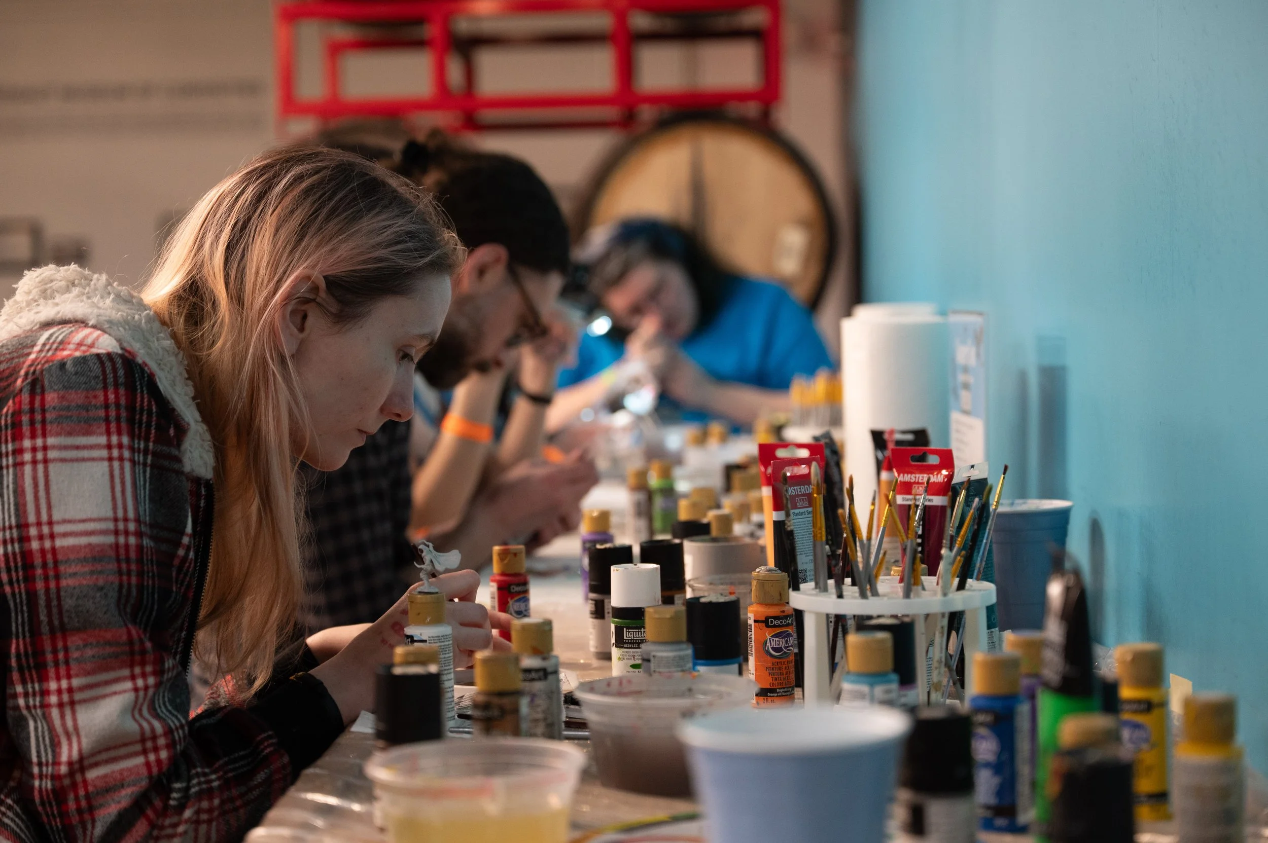 Located along the far wall of the barrel room is the miniature painting station, where attendees paint small figurines meant to represent various creatures found within tabletop games.
