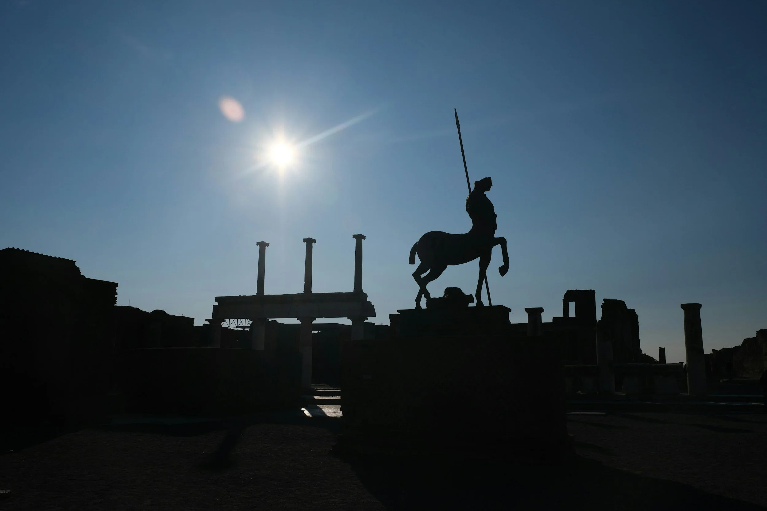 image of centaur statue and pillars in the distance at sunset