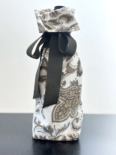 Upcycled fabric bottle bag in olive paisley pattern on a white background. Lining matches outside of bag. Bag has dark olive ribbon.