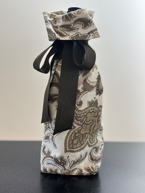 Upcycled fabric bottle bag in olive paisley pattern on a white background. Lining matches outside of bag. Bag has dark olive ribbon.