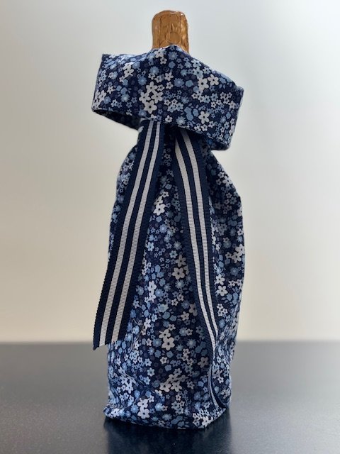 Upcycled fabric bottle bag in small floral pattern in shades of blue and white. Lining matches outside of bag. Bag has navy and white striped ribbon.