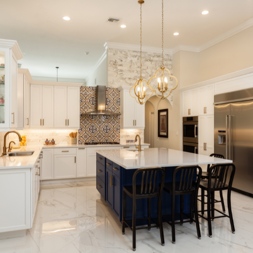Modern kitchen with white cabinets, a blue island, stainless steel appliances, and a chandelier over the island.