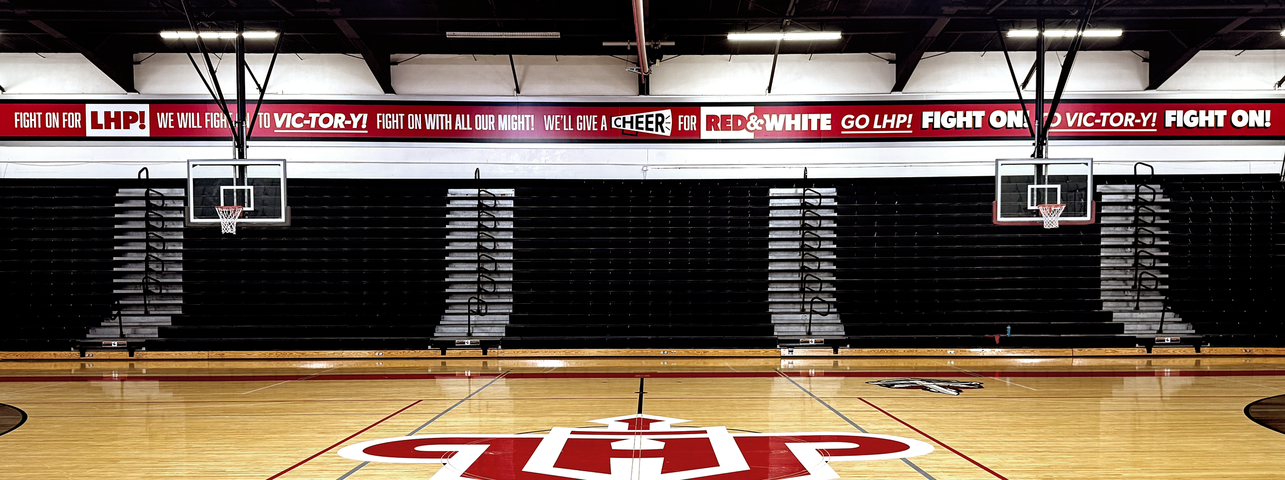 Weng family gym fight song graphic above bleachers.