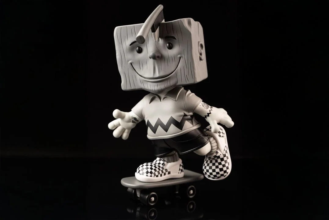 A figurine of a cartoon character with a box-shaped head, skateboarding against a black background.