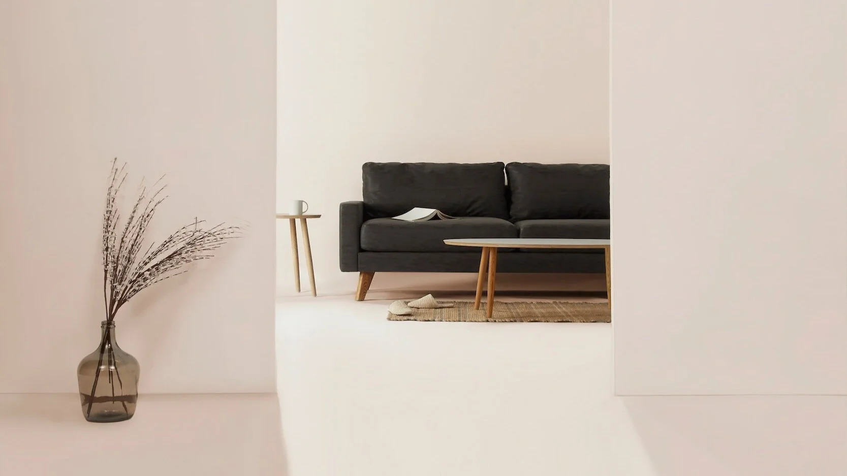 Minimalist living room with gray sofa, wooden coffee table, side table with a mug, decorative dried branches in a glass vase, and beige rug on light flooring. Serene therapy space in Winnipeg.