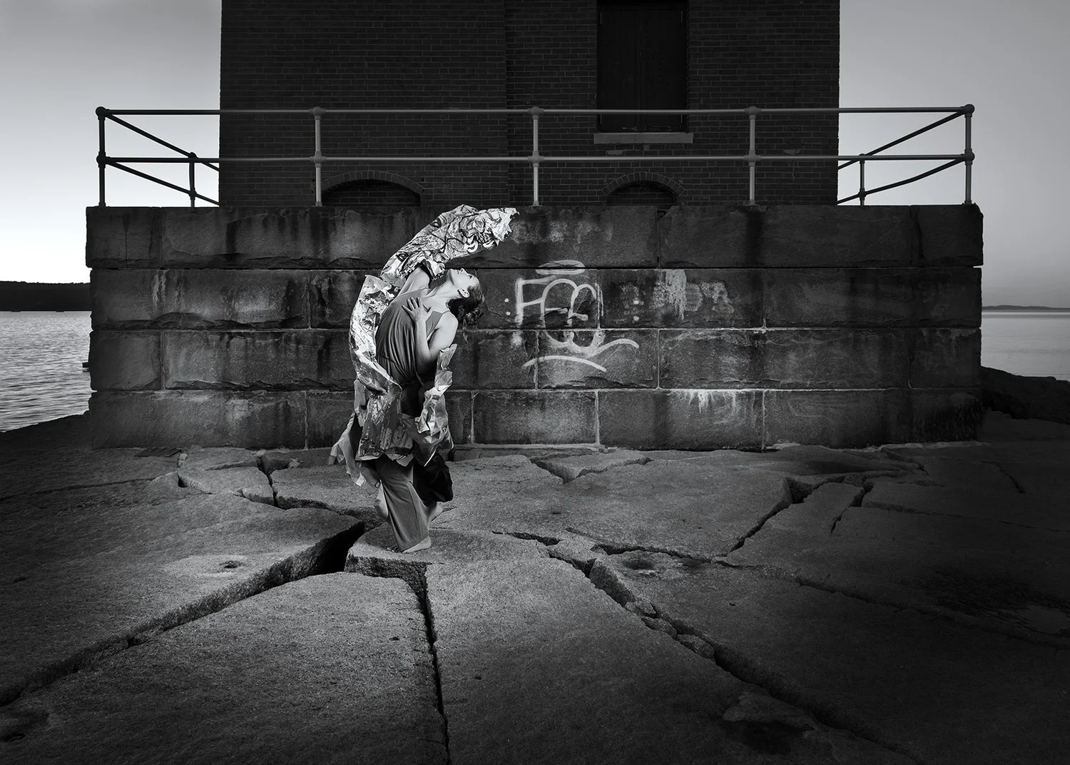 A woman dances with a shawl in front of a concrete wall
