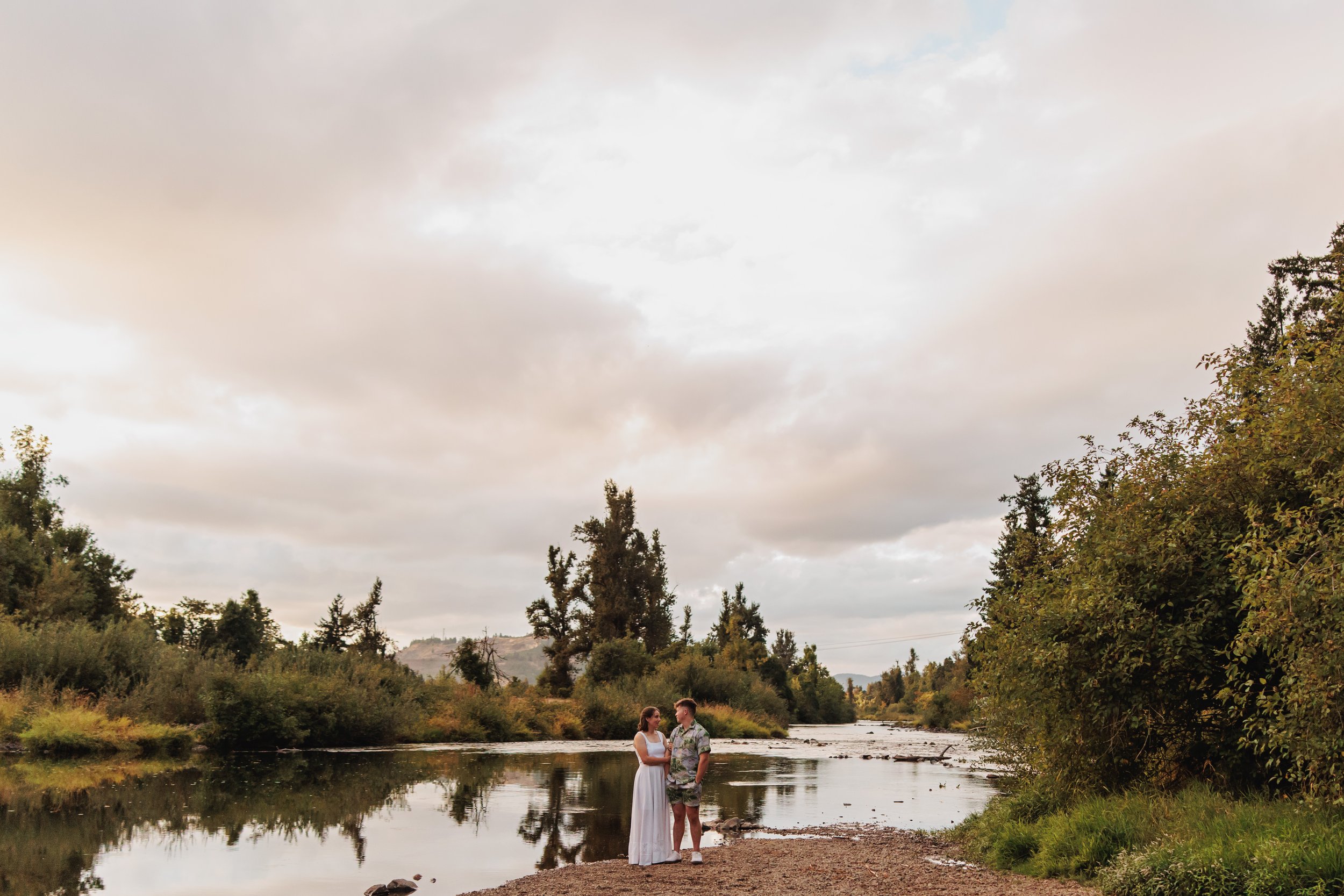 A couple stands beside the river after their nontraditional outdoor wedding ceremony at Mount Pisgah Arboretum in Eugene Oregon