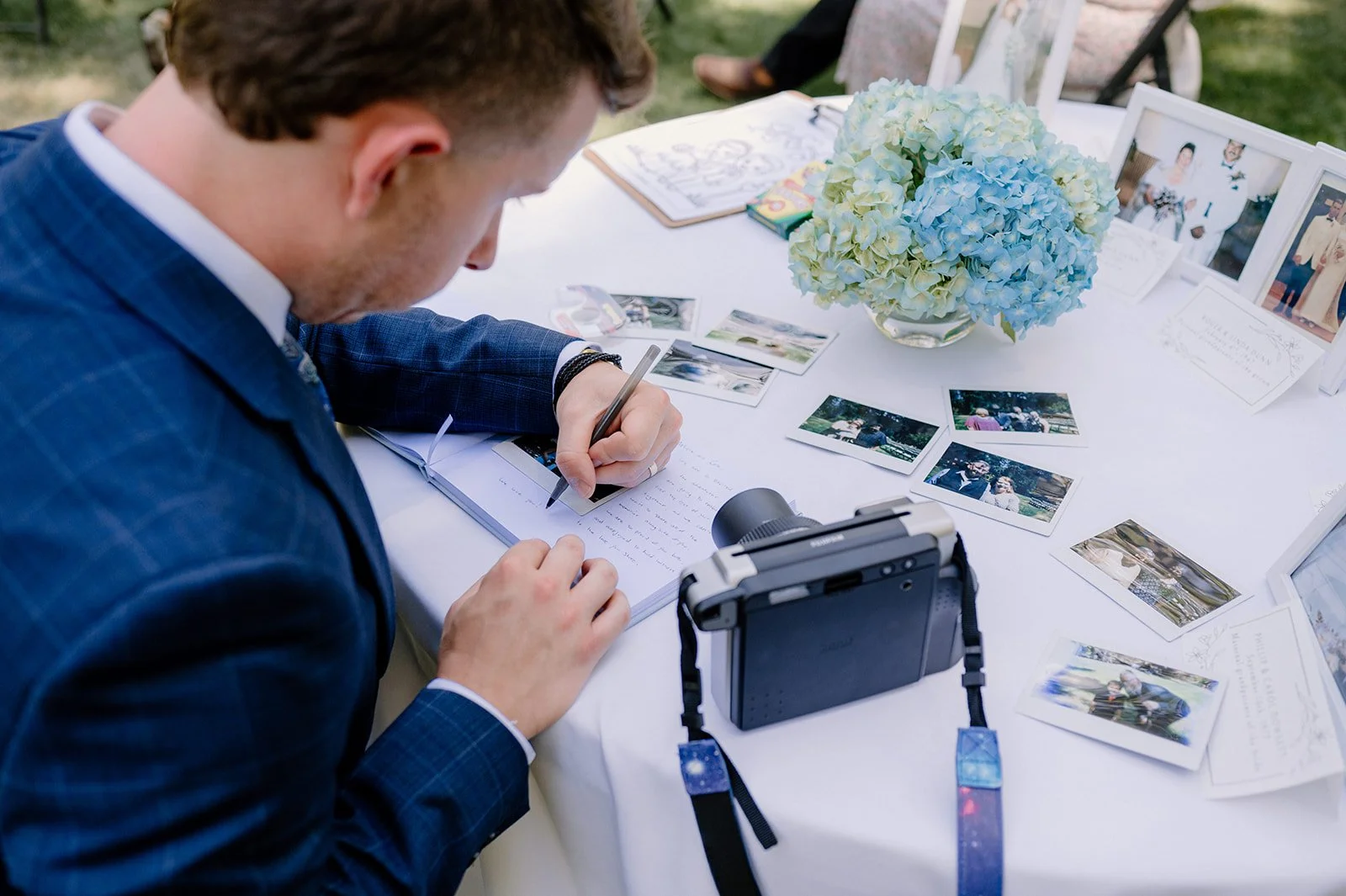 A wedding guest snaps a photo and adds a note to the guestbook at an outdoor wedding near Eugene, Oregon
