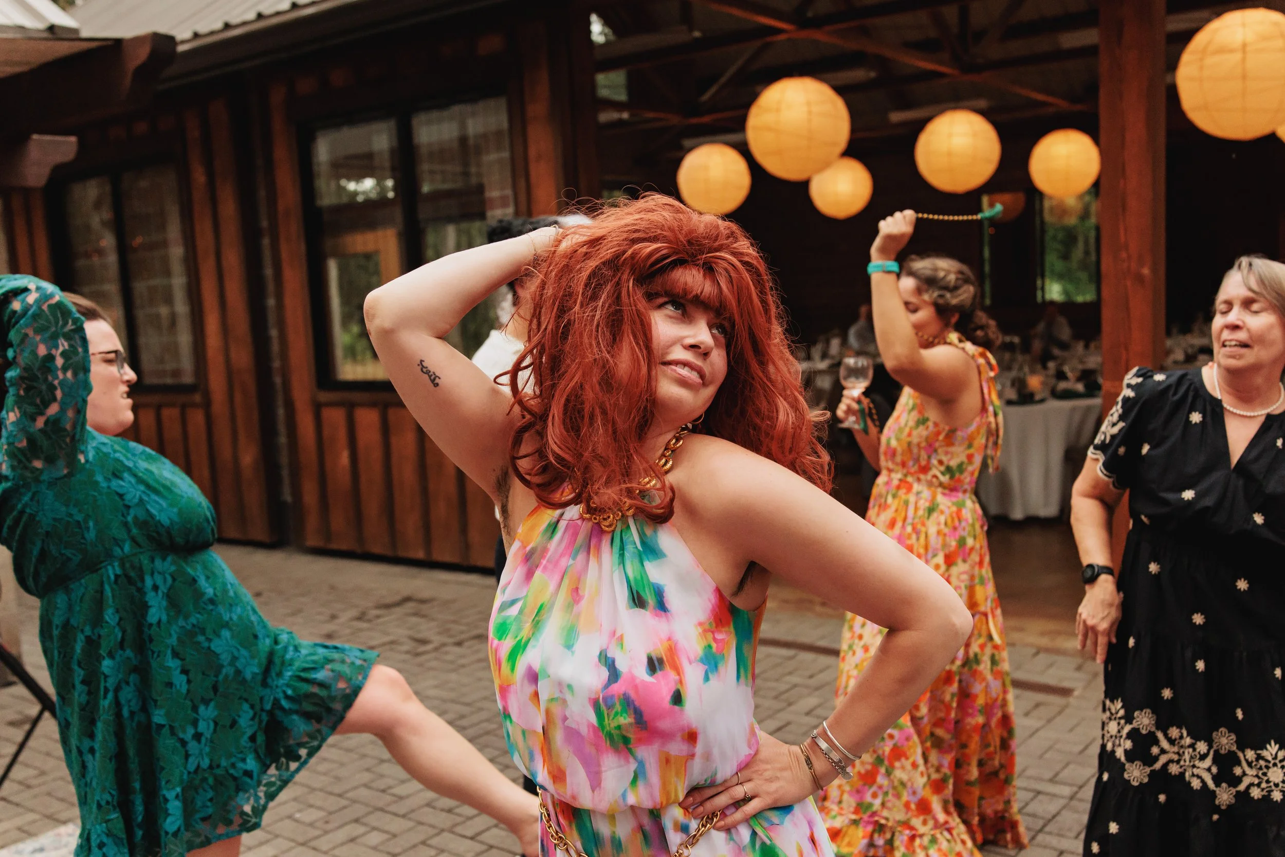 Wedding guests don costume wigs and dance during a reception at Mount Pisgah Arboretum in Eugene, Oregon