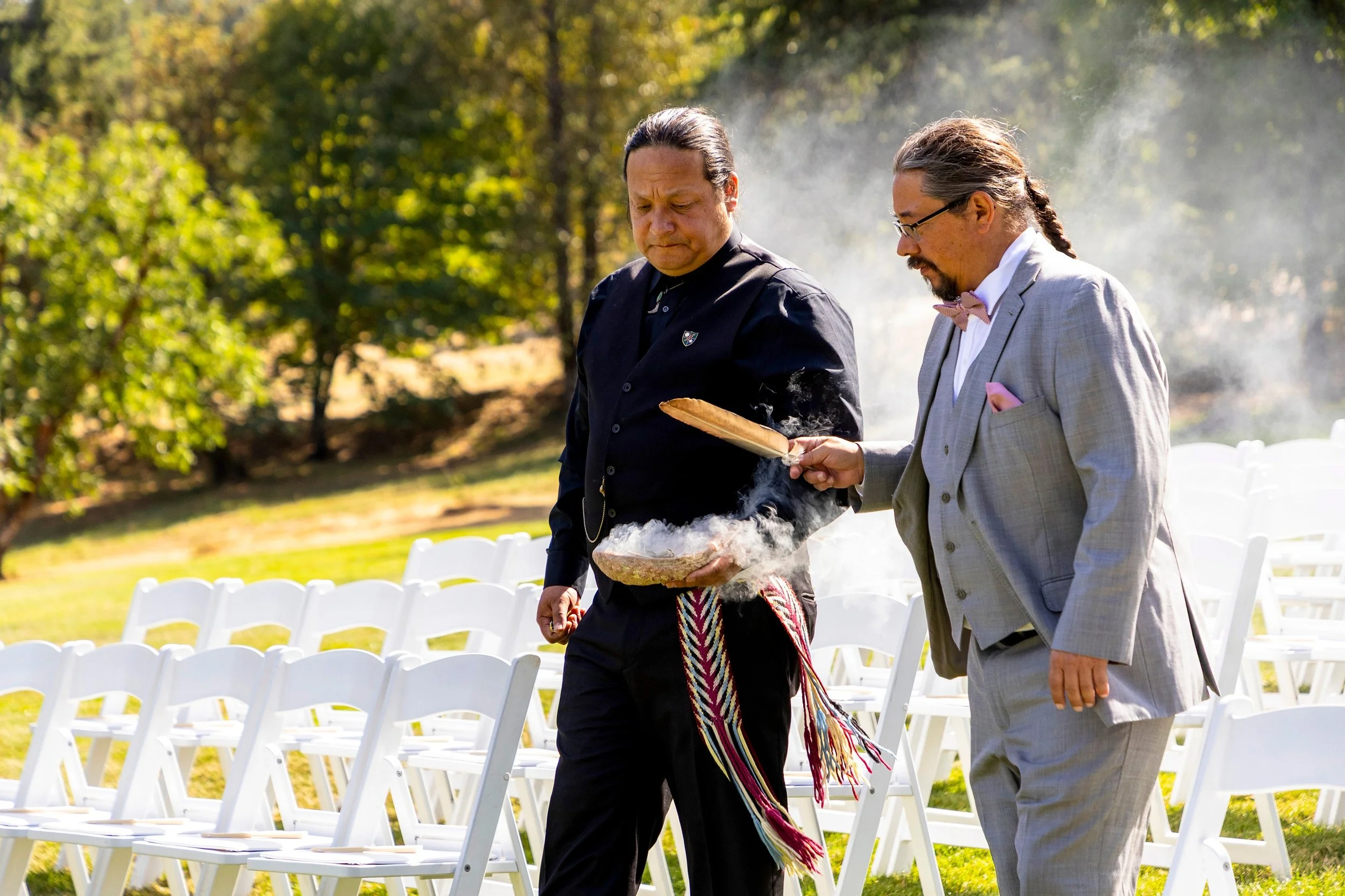 Two men carry sacred herbs towards the altar at a wedding incorporating native american traditions