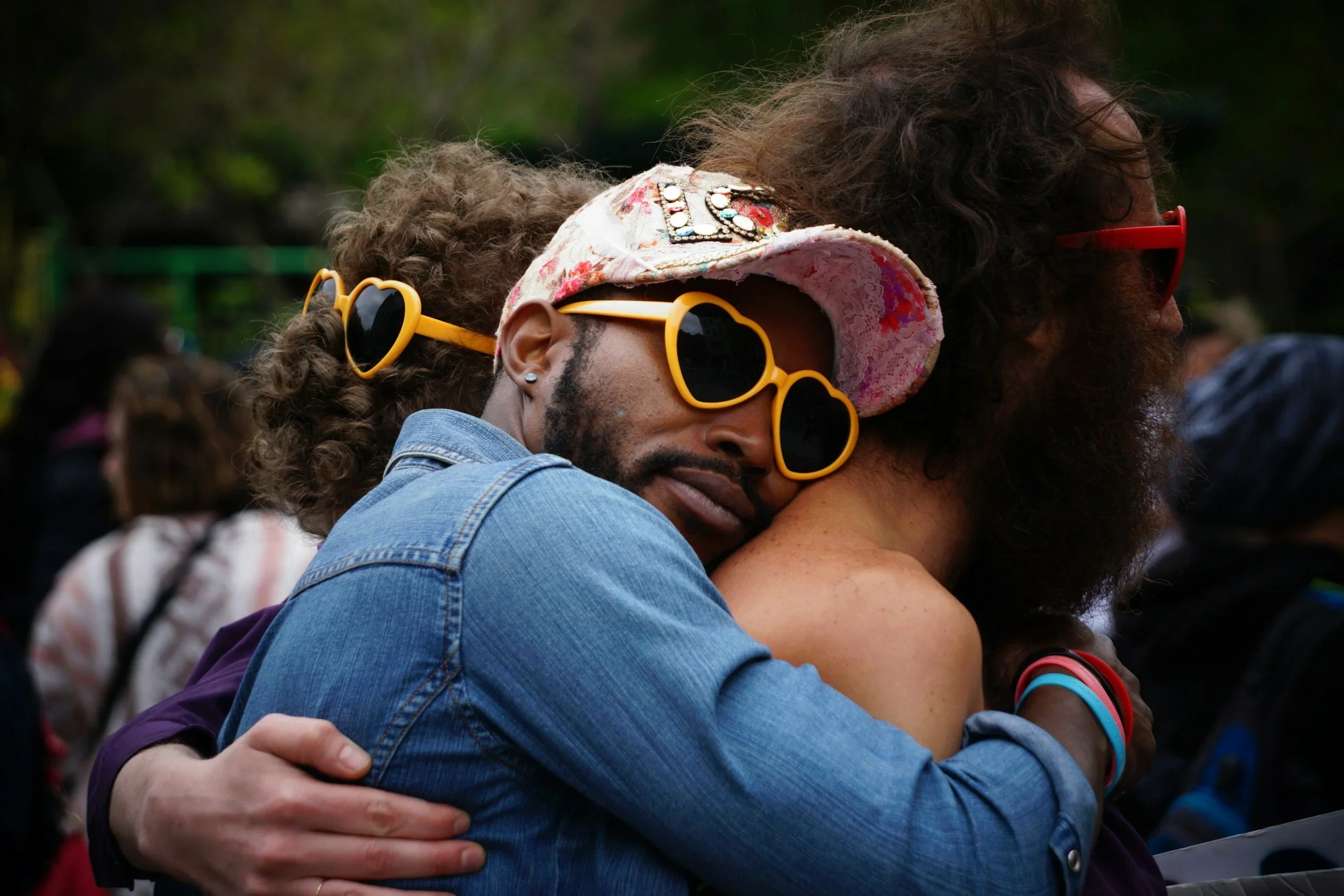 three people who are in a polyamorous relationship hug and are showing affection to each other in their non-monogamy and receiving therapy from a queer nonbinary therapist based in Los Angeles.