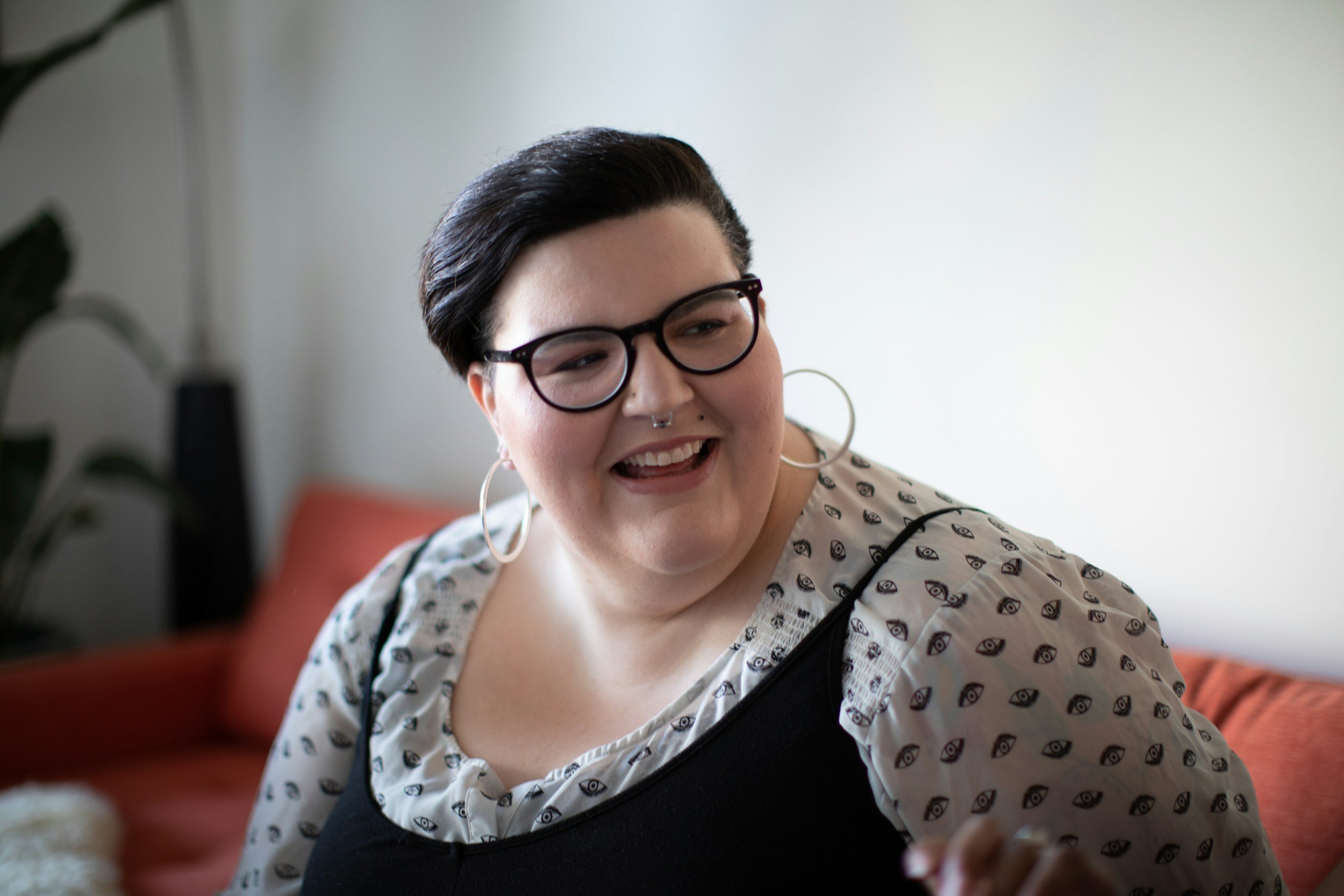 Person smiling during a conversation in a comfortable setting, representing supportive therapy for artists, creatives, and people with multi-hyphenate lives.