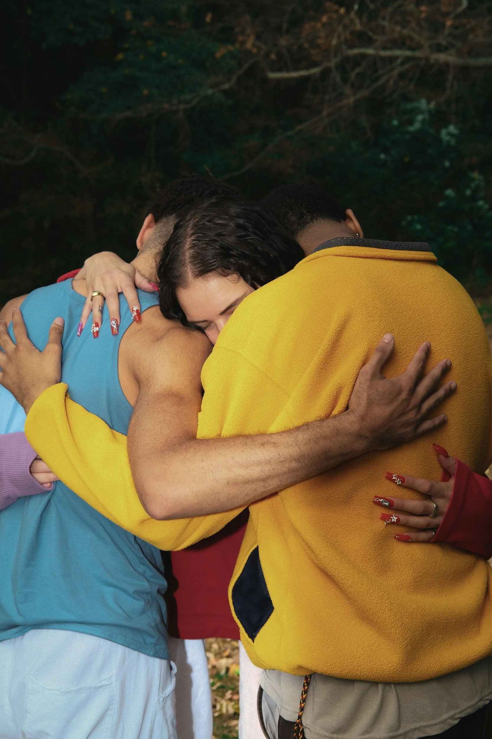 Three people in a close group hug in colorful outfits — kink-affirming, sex-positive therapy for relationship-diverse adults in Los Angeles and California
