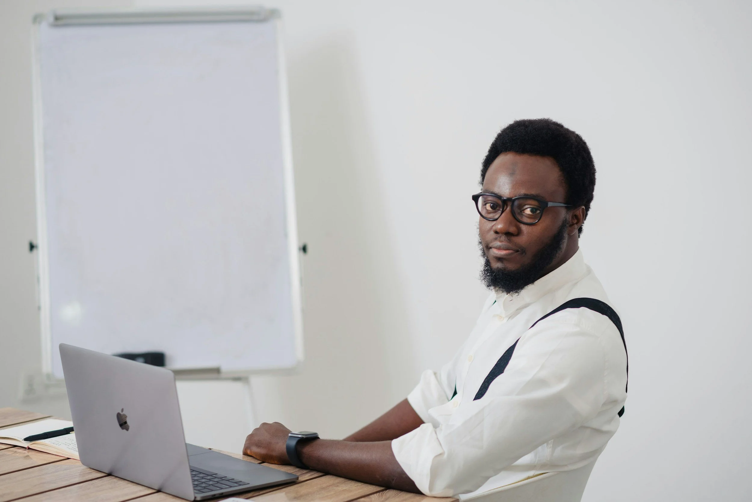 A man in a reflective, vulnerable pose at a desk, gently touching his face as a tear track is visible, representing the emotional depth and somatic experience of men accessing internal wisdom.