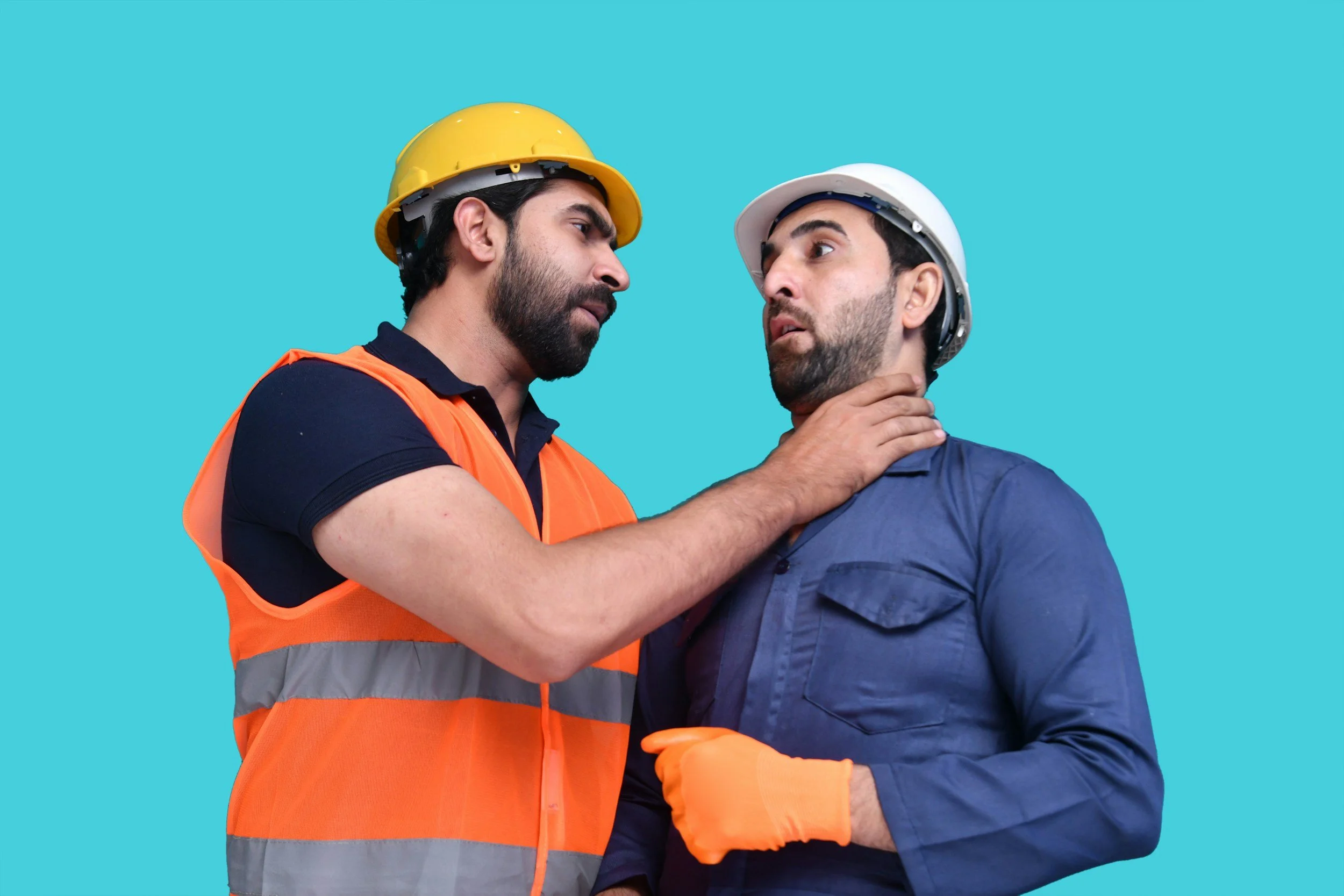 Two workers wearing hard hats and high-visibility vests engaged in a tense interpersonal conflict.