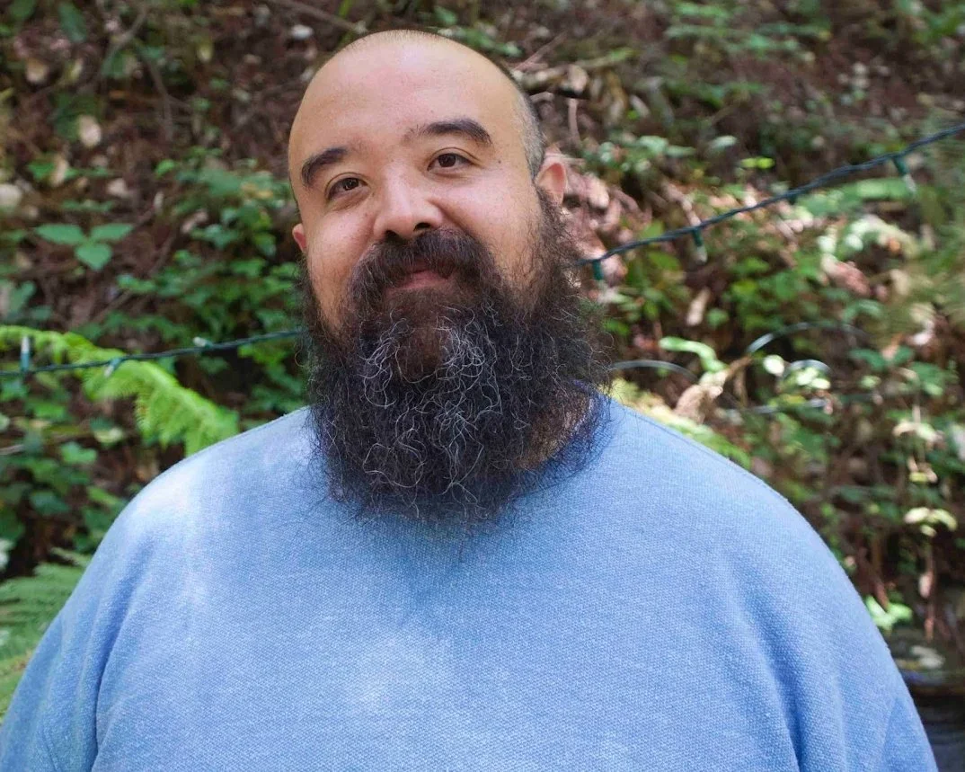 Edgar Fabián Frías, LMFT, smiling warmly outdoors in a green natural setting