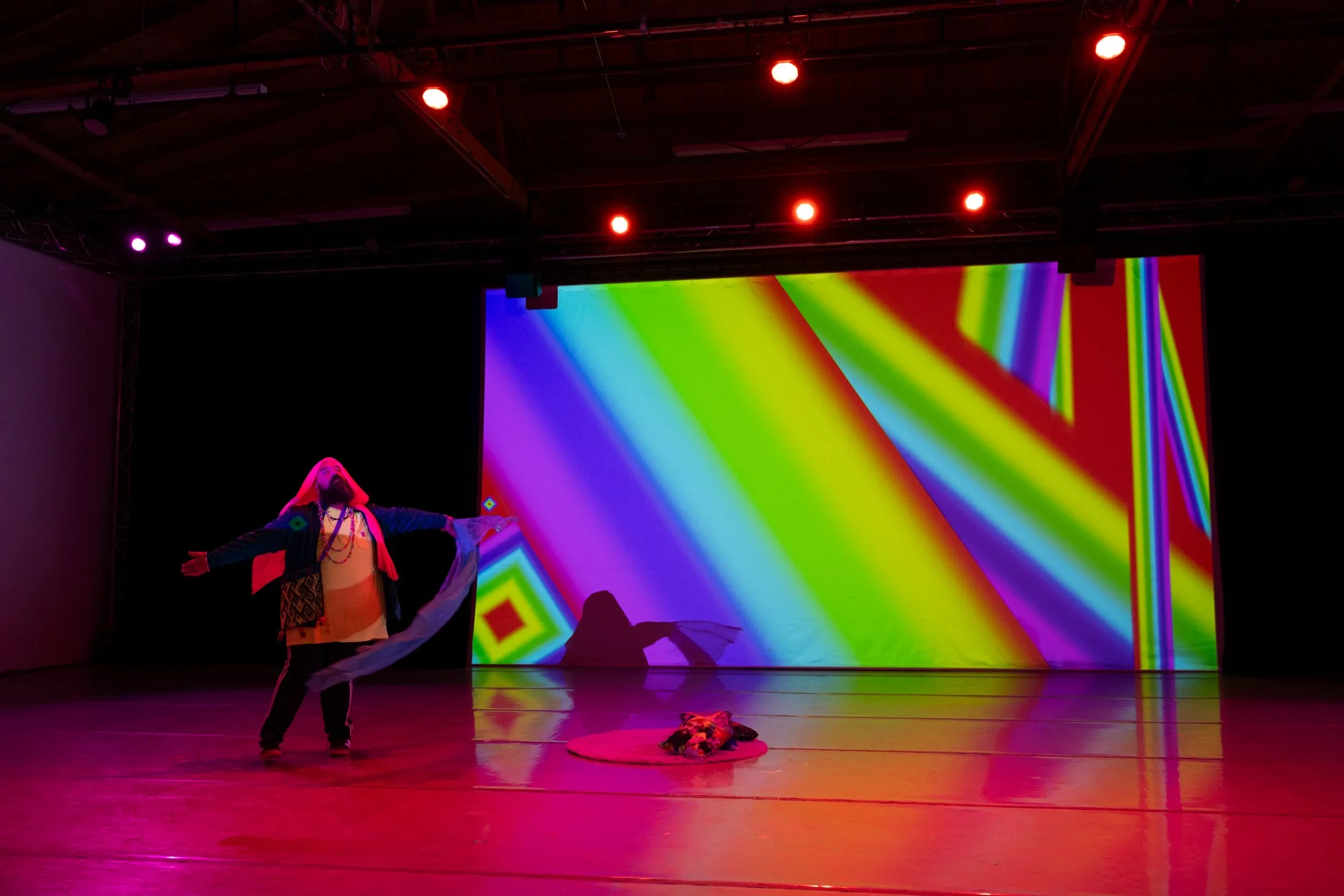 Therapist who is also a practicing artist performing on stage with vibrant projections, reflecting embodied, creative-informed therapy for artists and multi-hyphenates in California.