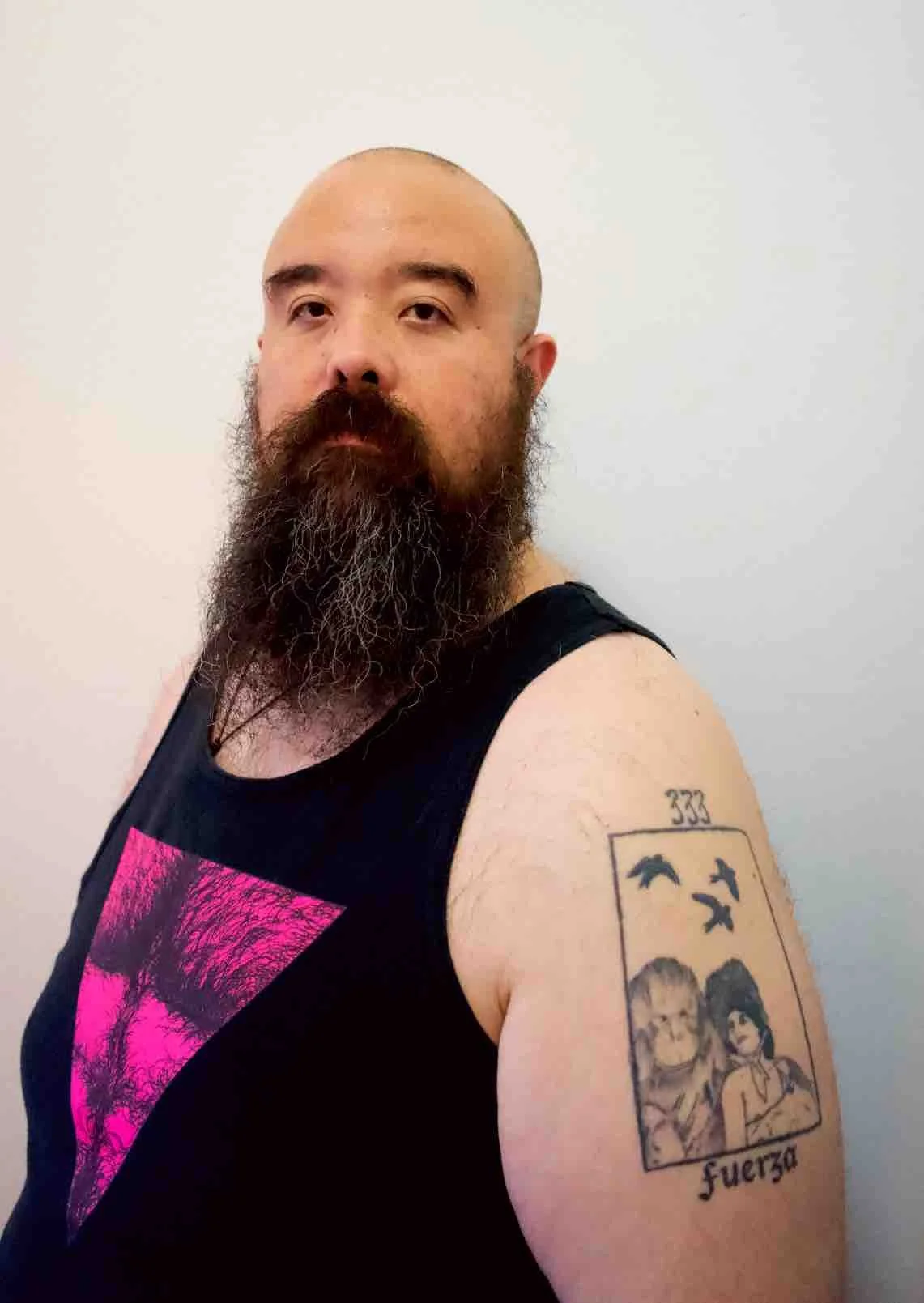 Portrait of Edgar Fabián Frías, a nonbinary therapist w/ a beard & tattoo of Strength tarot card, representing their role as a gender-affirming therapist for nonbinary, gender expansive, & gender nonconforming clients in California.