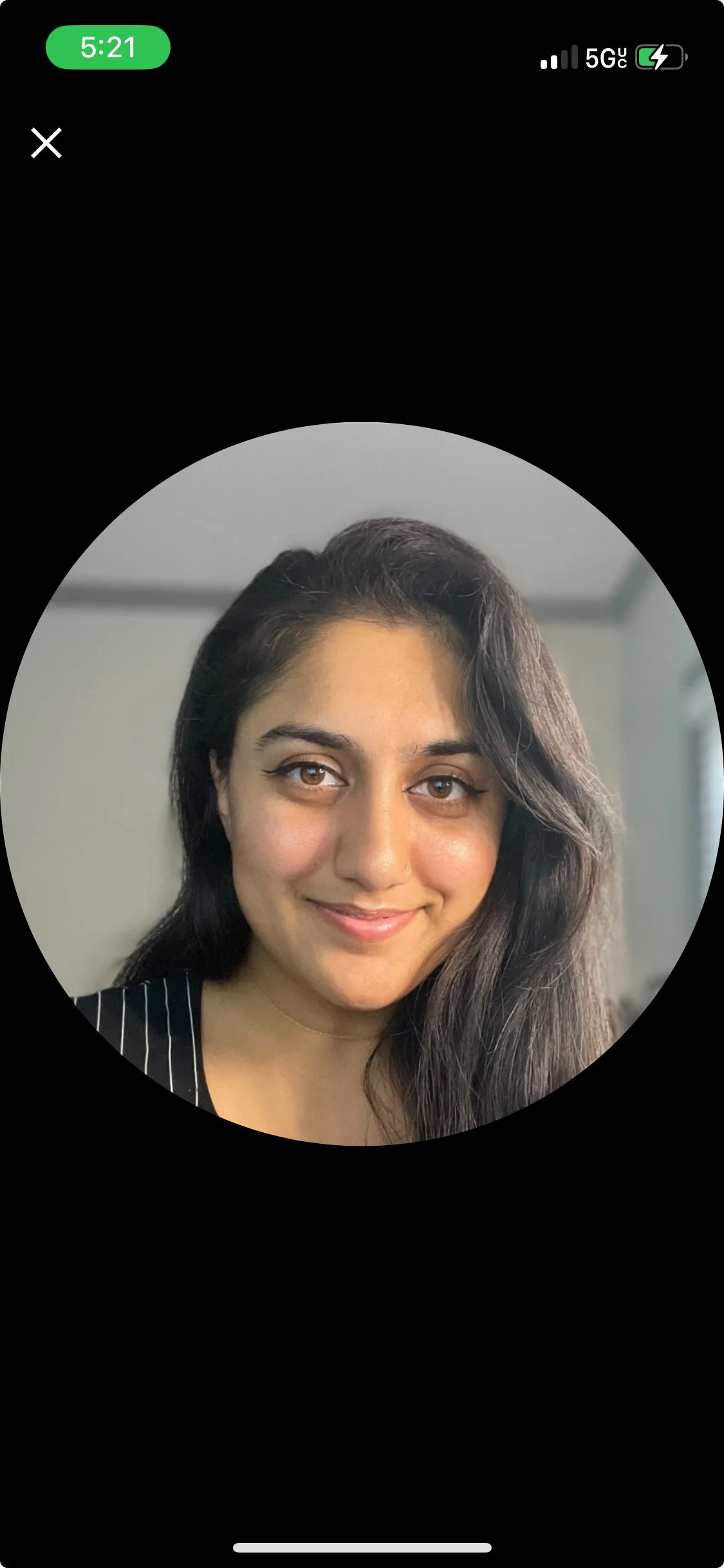 A young woman with long dark hair, light brown eyes, and a light smile, wearing a black top with white pinstripes, indoors with a neutral-colored wall in the background.