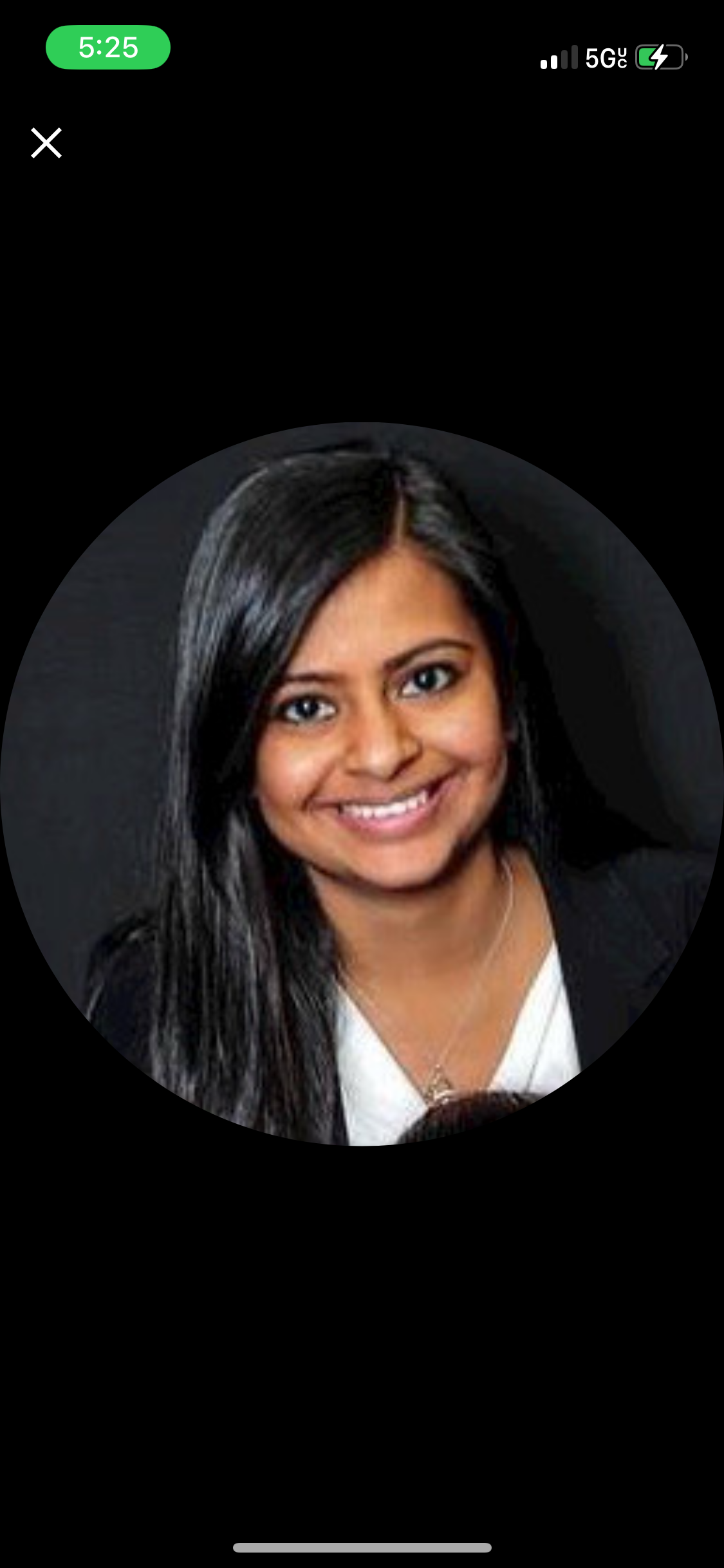 Portrait of a smiling woman with long black hair, wearing a white blouse and a black blazer.