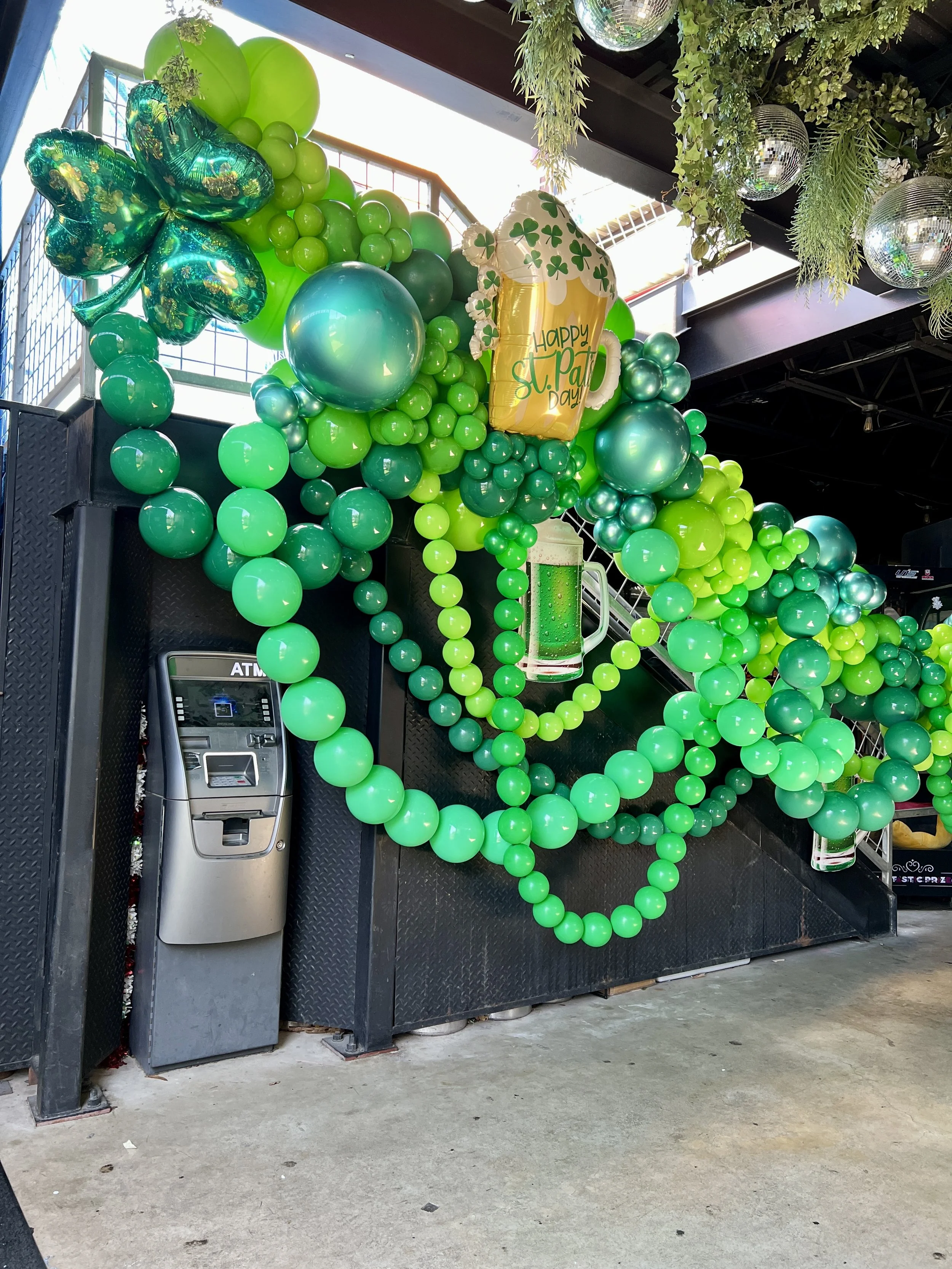 Organic St. Patrick’s Day balloon garland decorating the staircase at Lucky Duck Bar featuring festive green balloon décor in San Antonio, Texas.
