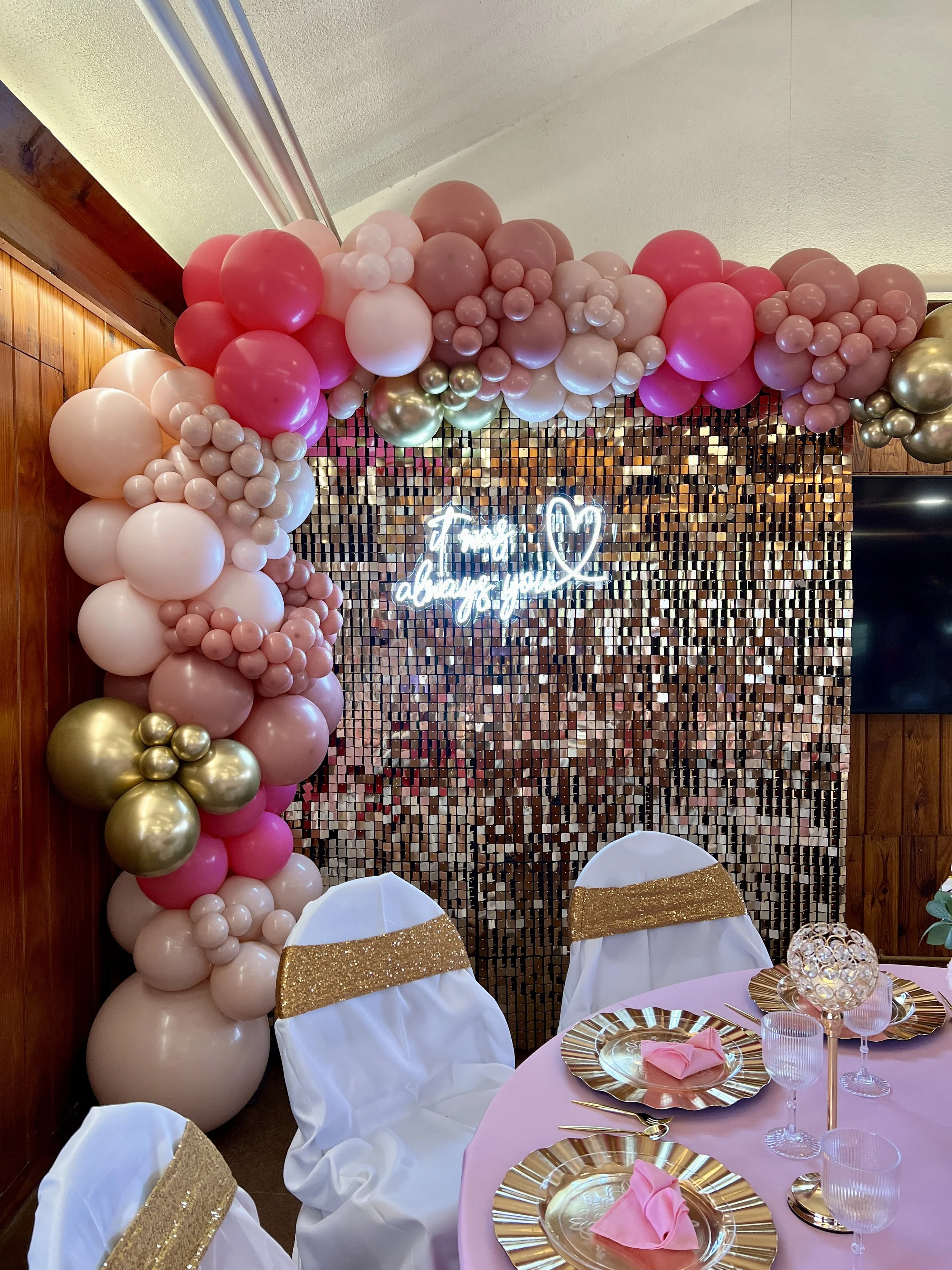 Gold shimmer wall with balloons and full table decorations