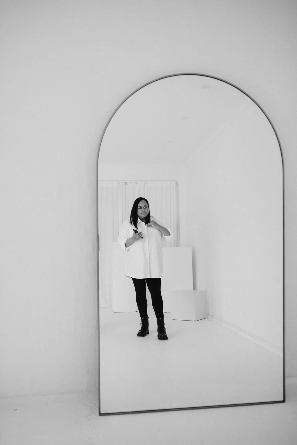 Sherise Adkins standing in a white minimalist studio, holding a marker
