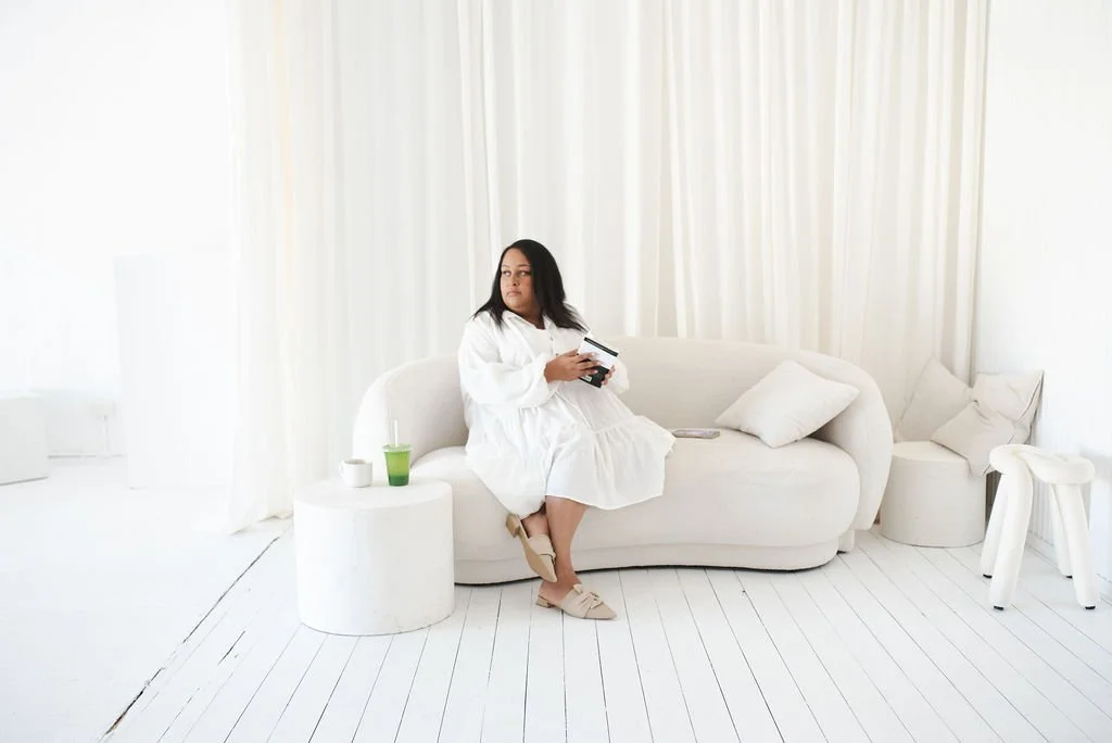 Sherise Adkins sitting on a cream sofa in a white robe with an iced green drink beside her