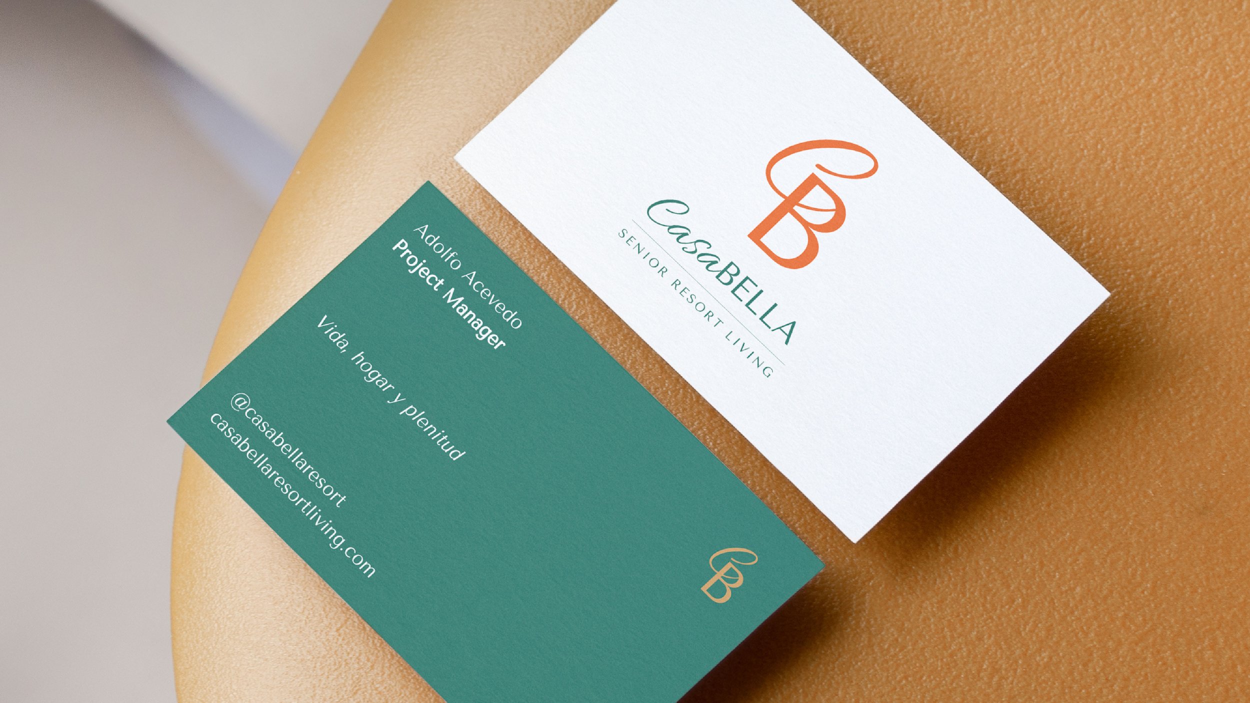 Business card from Casa Bella Senior Resort Living, displaying the name 'Adolfo Acevedo, Project Manager,' with contact information and social media handles placed on a teal section below the logo.