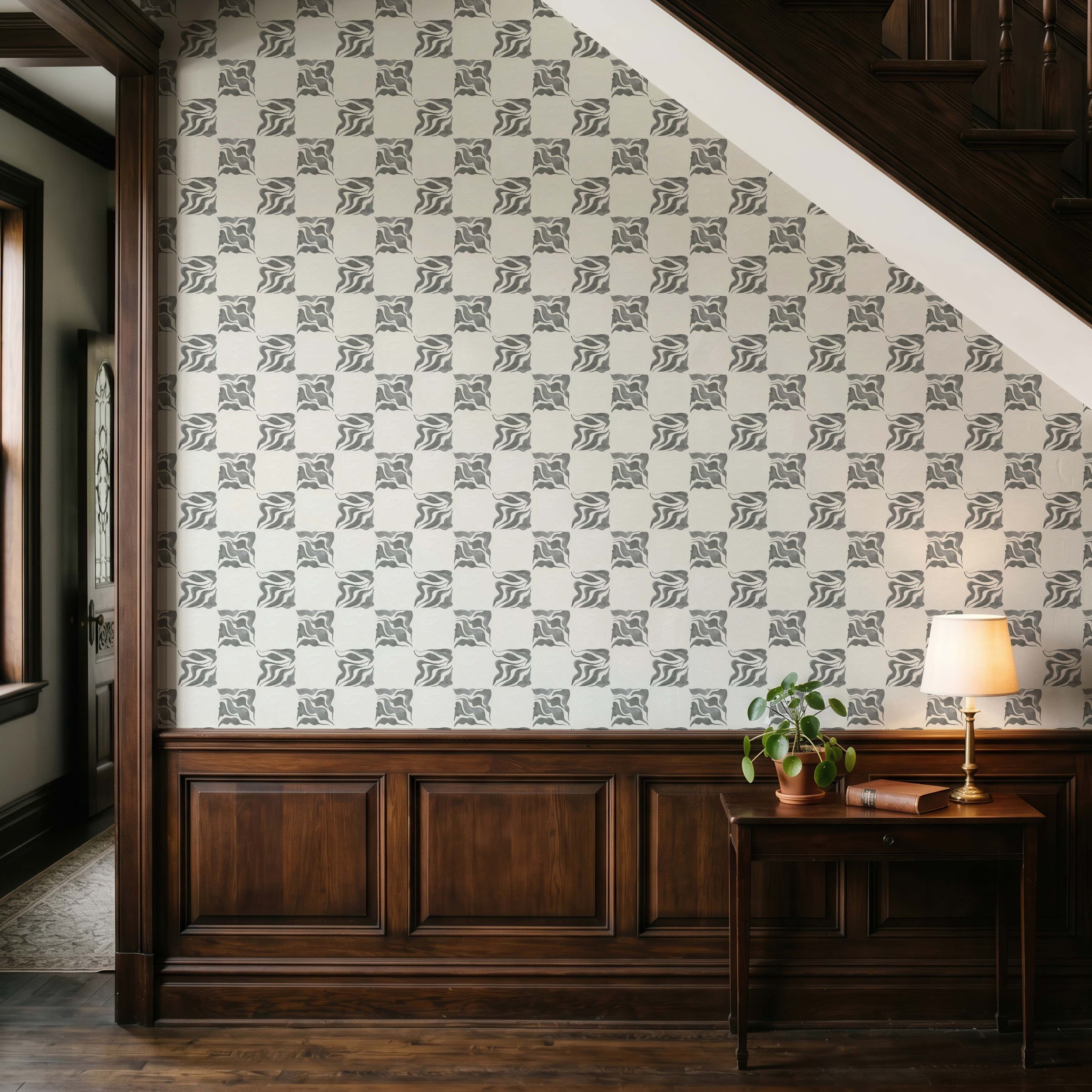 Wooden kitchen island with a small potted plant and a lamp on it, and patterned wallpaper on the wall behind.