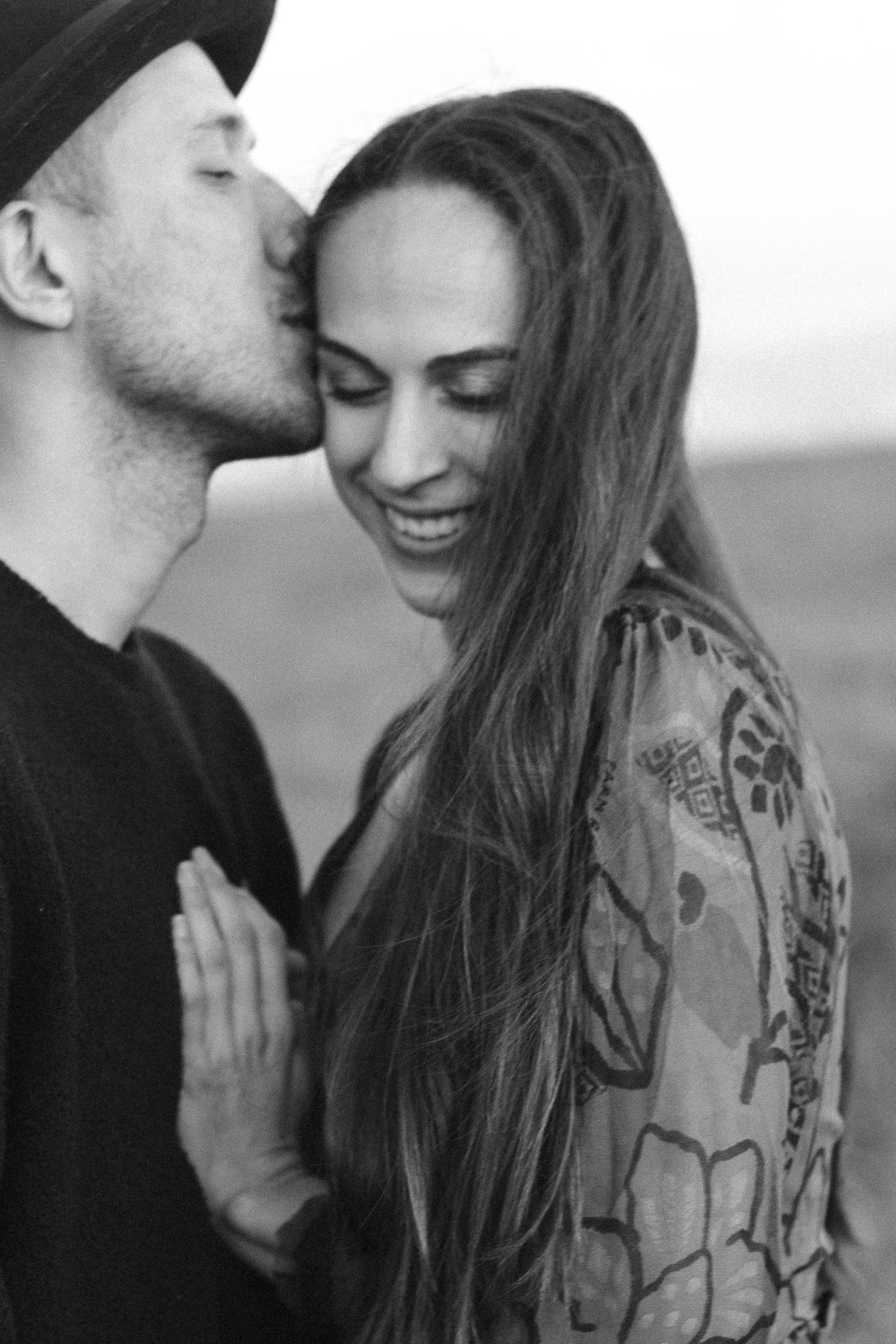couples photoshoot - A black and white photo of a young couple sharing a kiss. Both have their eyes closed, and the woman is smiling slightly.